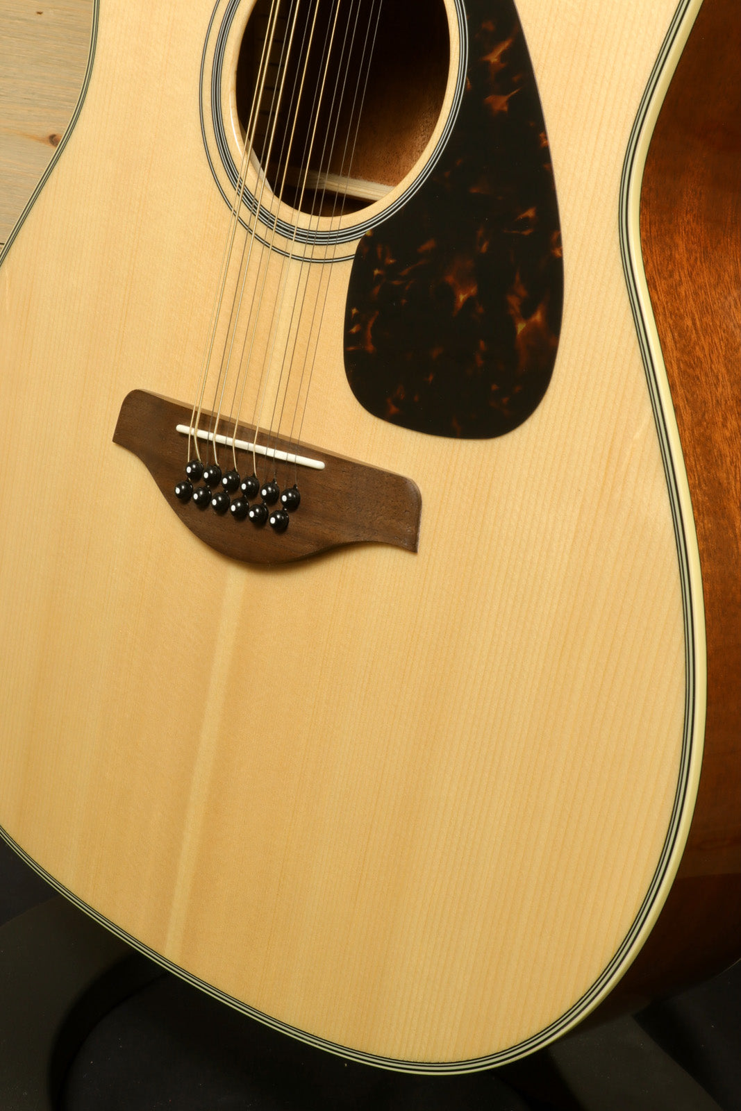 Yamaha acoustic guitar natural finish, front view showing body and bridge