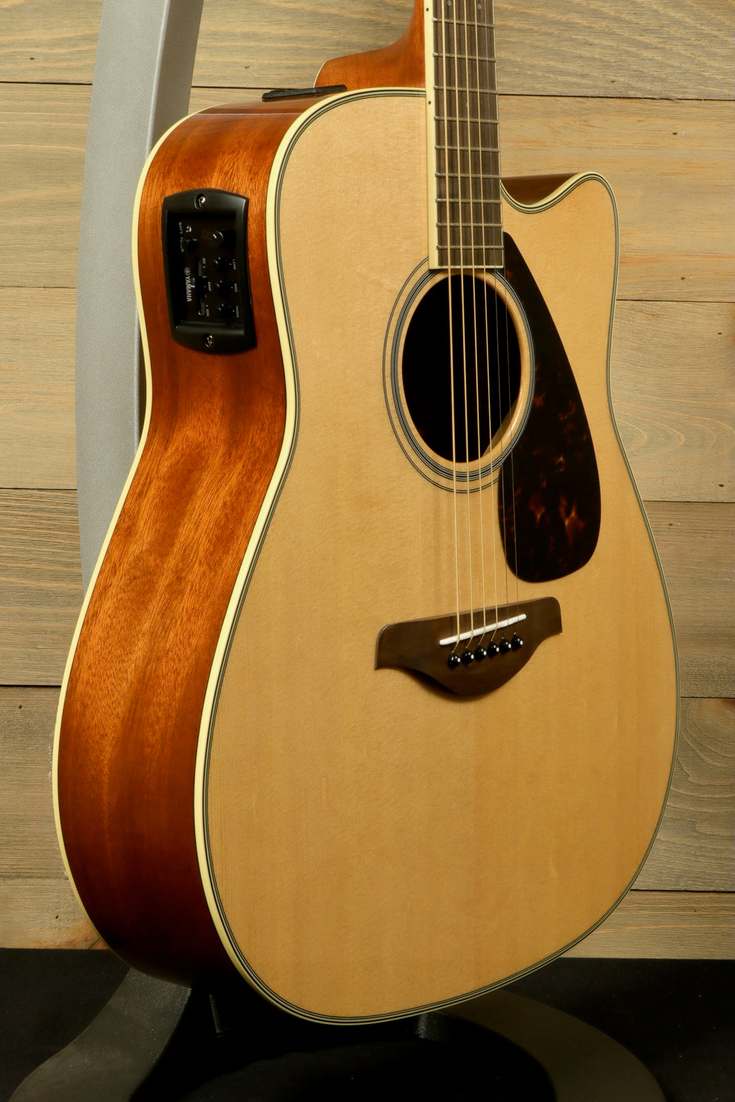 Yamaha acoustic electric guitar in natural finish, showcasing fine wood grain and integrated pickup system, side view