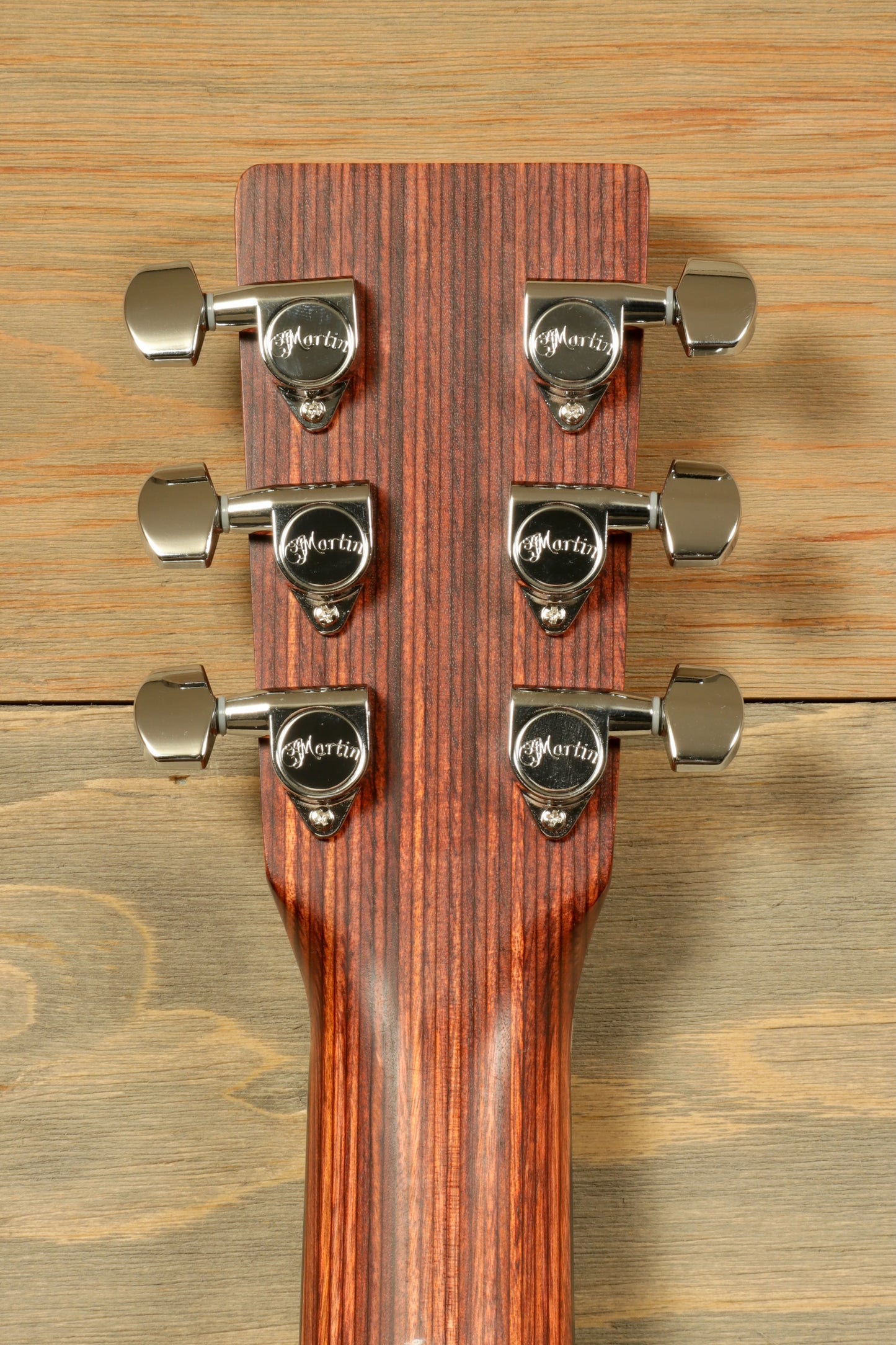 Back view of Little Martin acoustic guitar headstock with chrome tuning pegs on wood background