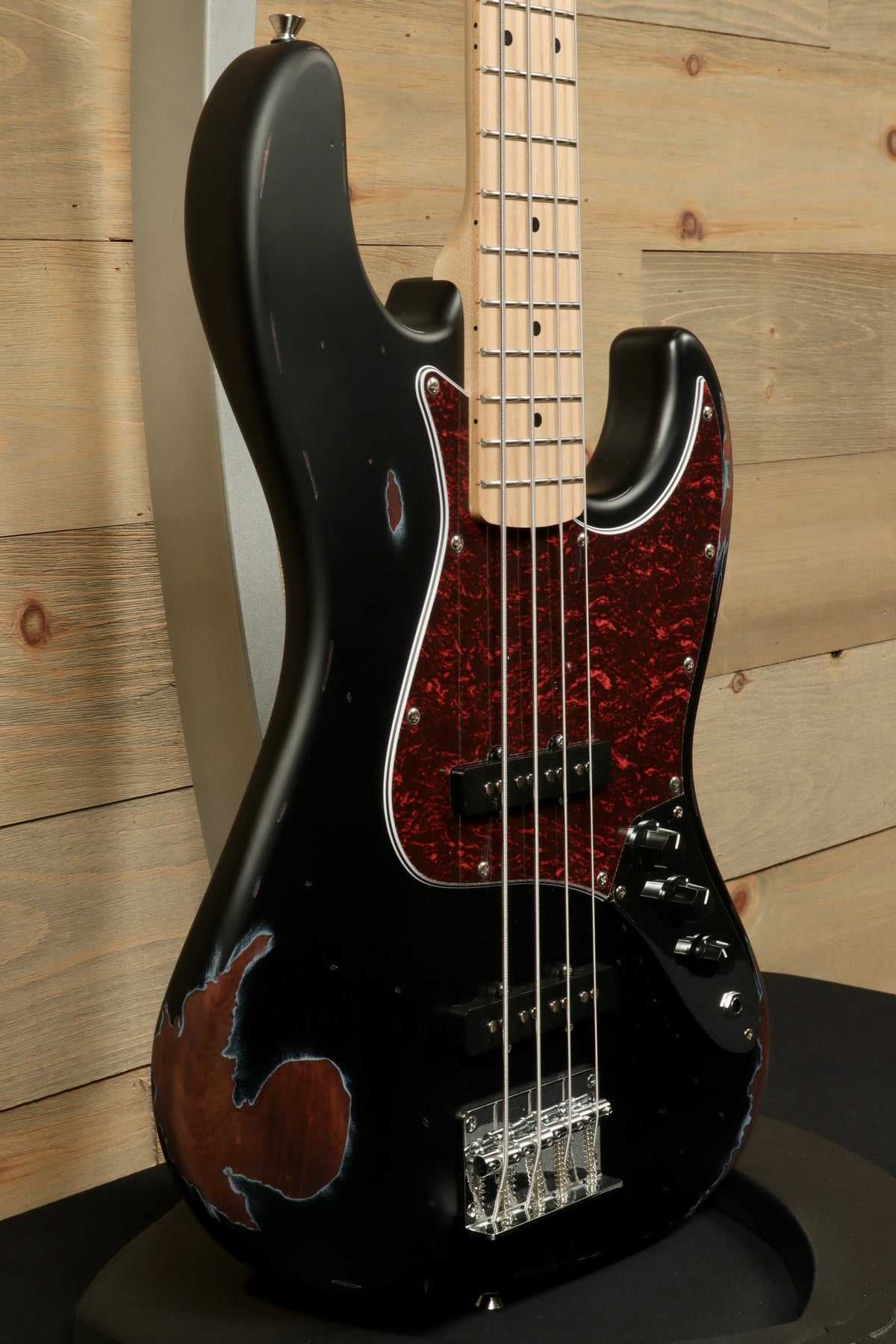 Tagima TBA-73 Electric Bass in black with a red tortoiseshell pickguard, side view