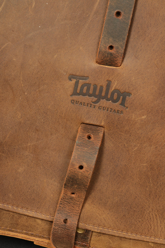 Close-up of Taylor Guitars messenger bag showcasing the embossed logo on premium leather