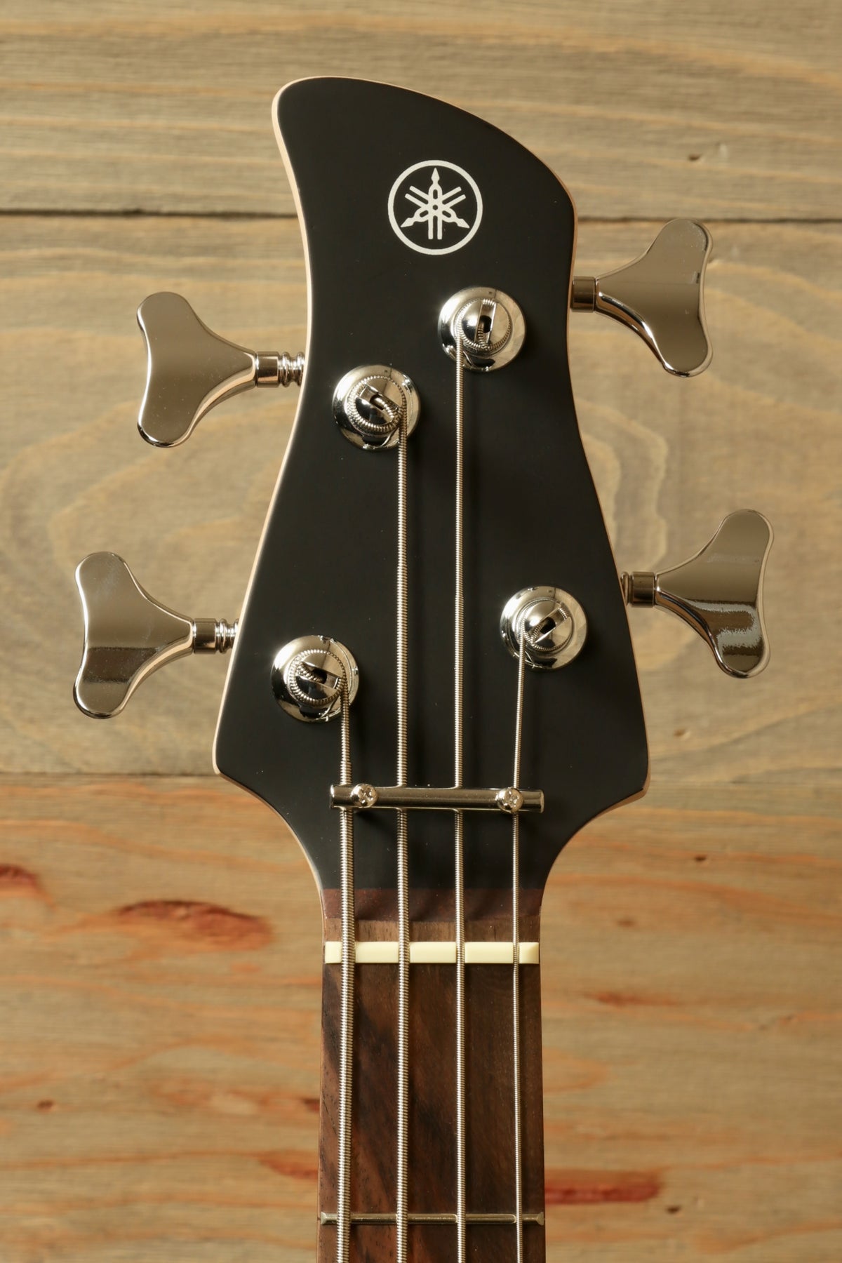 Yamaha TRBX174 black bass guitar headstock with tuning pegs, front view