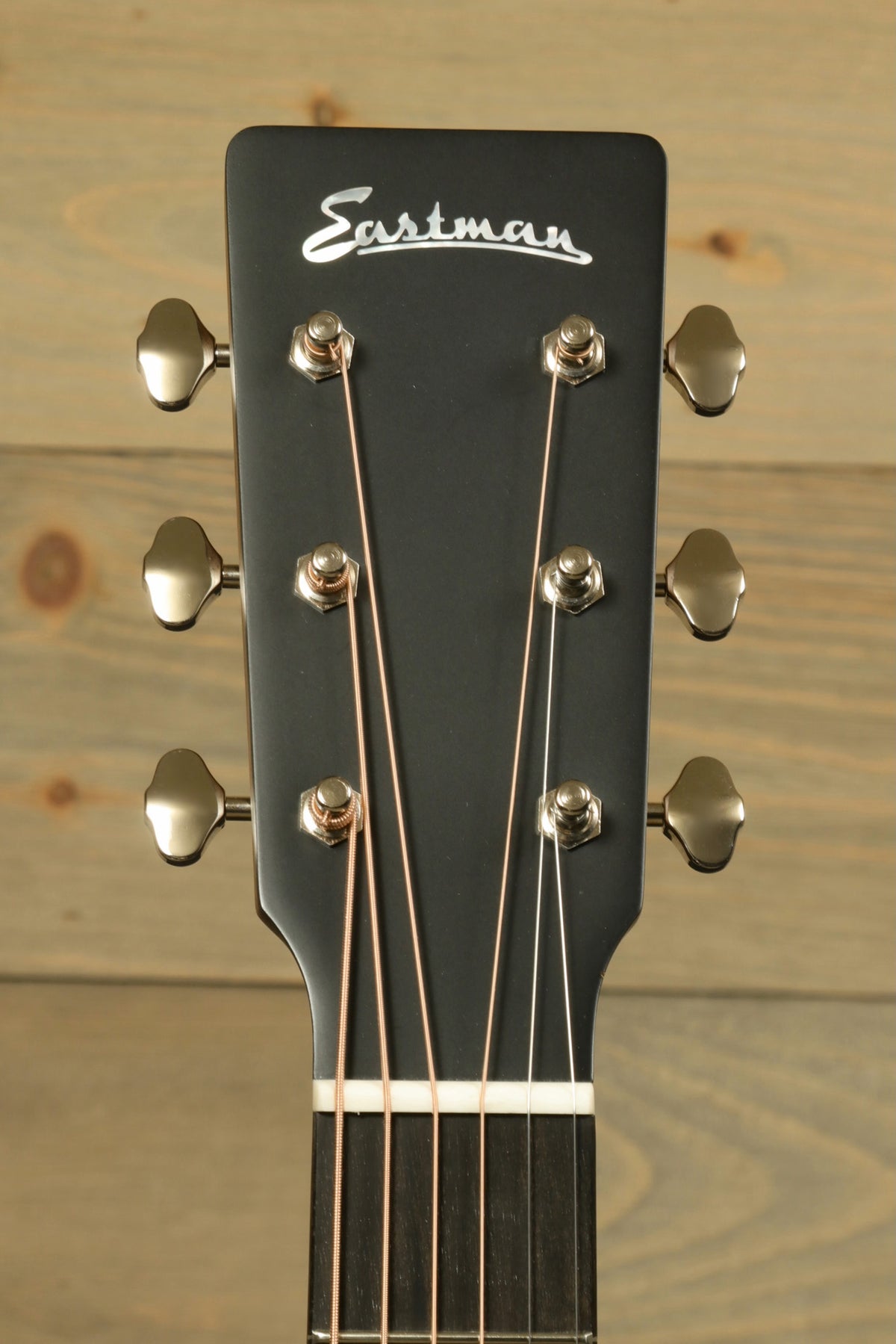 Image of the headstock of the Eastman E3OME acoustic guitar, featuring the brand logo and tuning pegs.