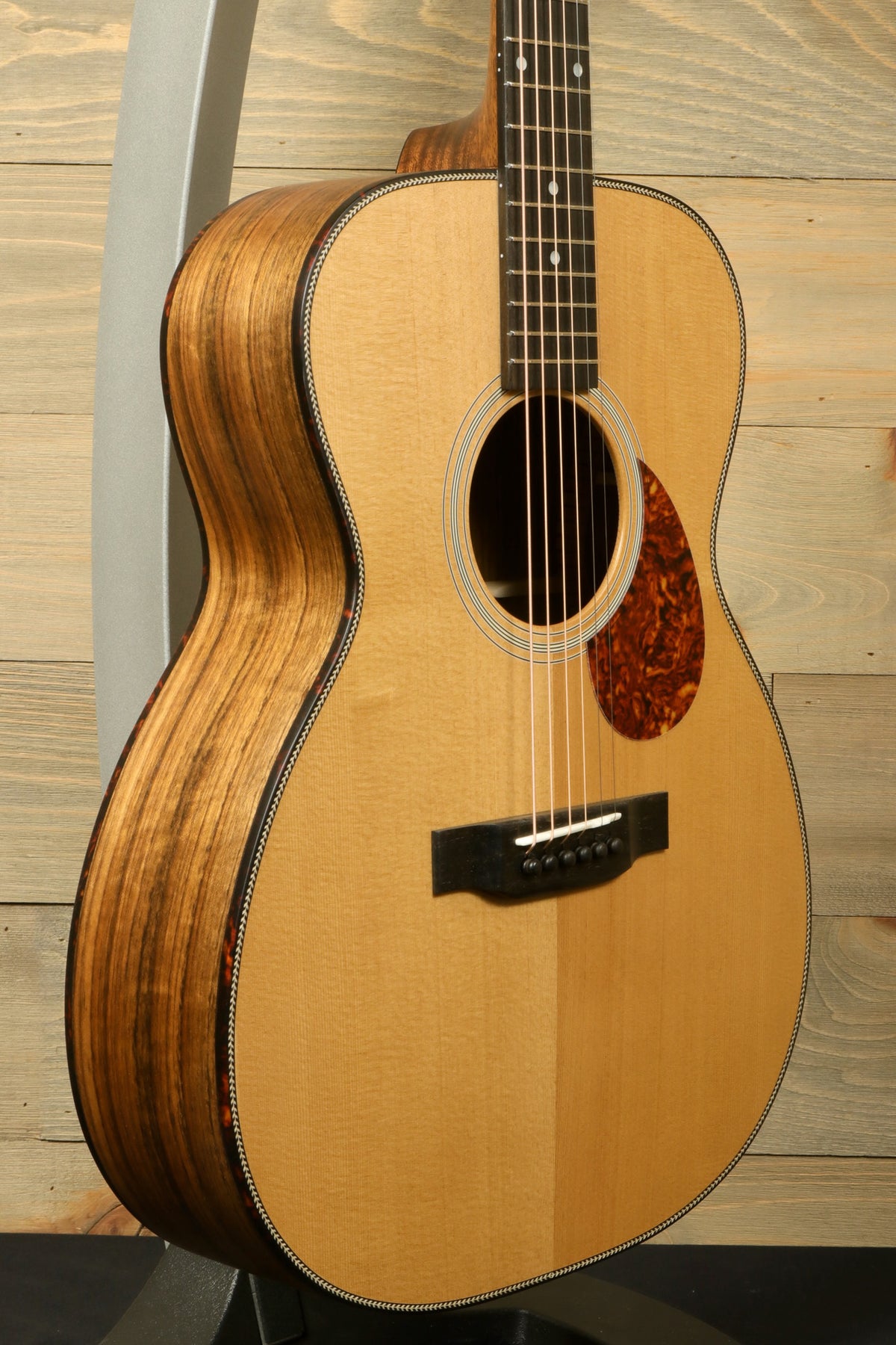 Side angle view of the Eastman E3OME acoustic guitar displaying its curvy body shape, solid Sitka spruce top, and stunning wood binding.