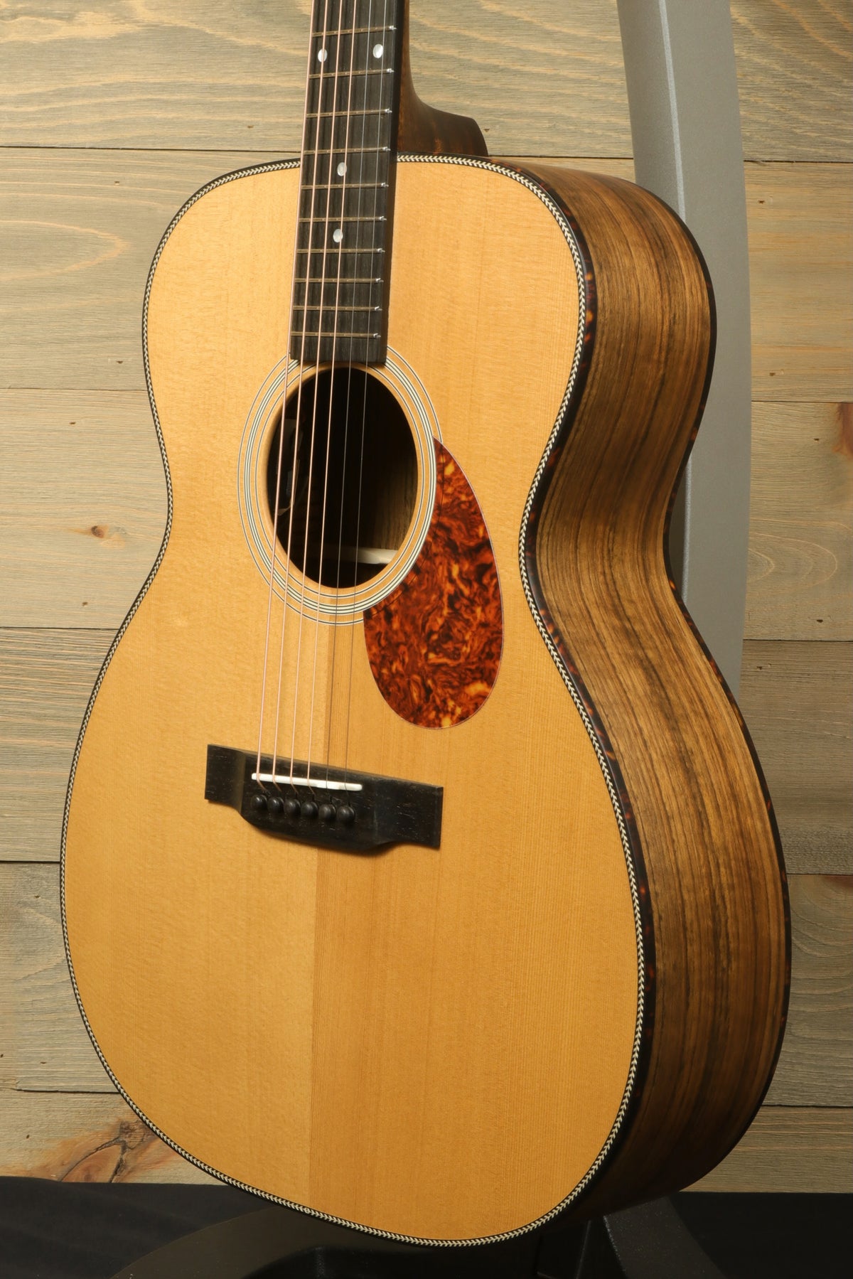 Side profile of the Eastman E3OME acoustic guitar showing the detailed construction of the body, with elegant binding and a tortoise shell pickguard.