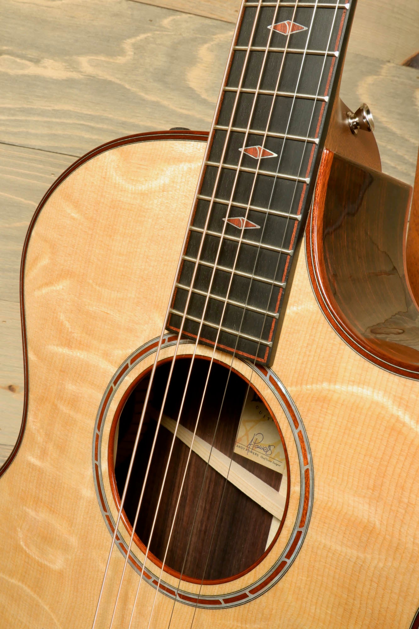 a close up of a guitar on a wooden surface