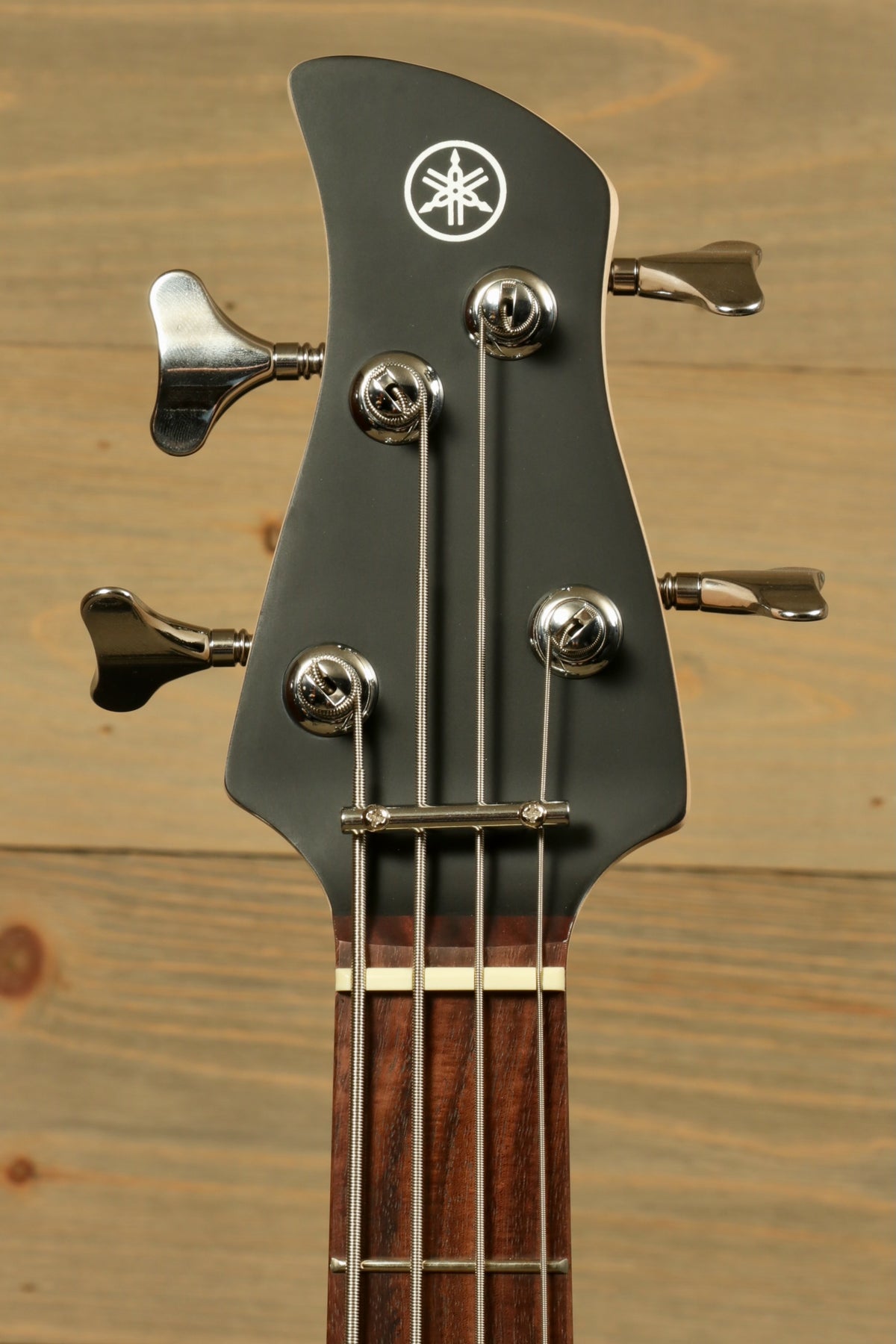 Yamaha TRBX174 black finish bass guitar headstock with chrome tuning pegs, front view