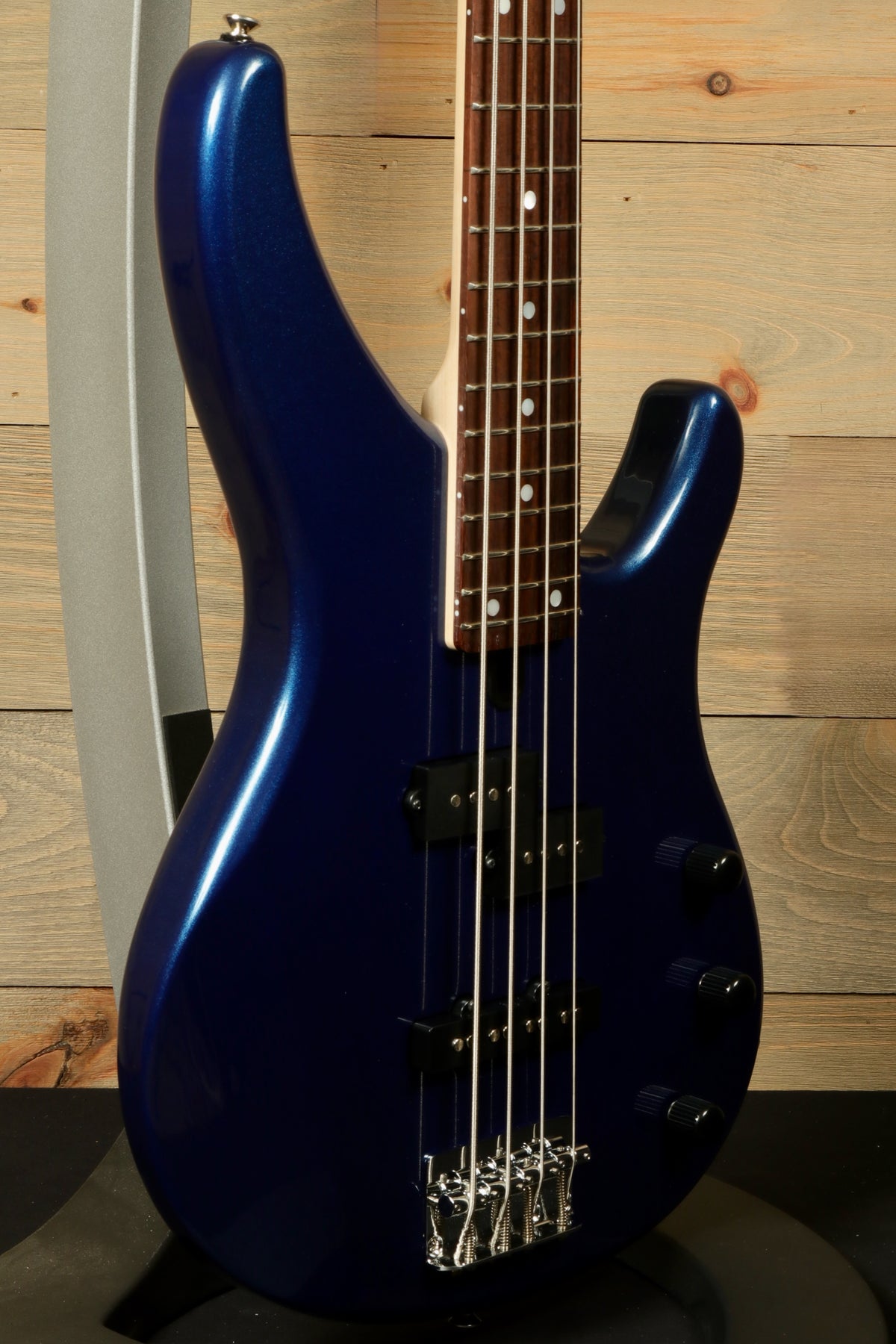 Yamaha TRBX174 bass guitar in deep blue, side view showing body and neck details