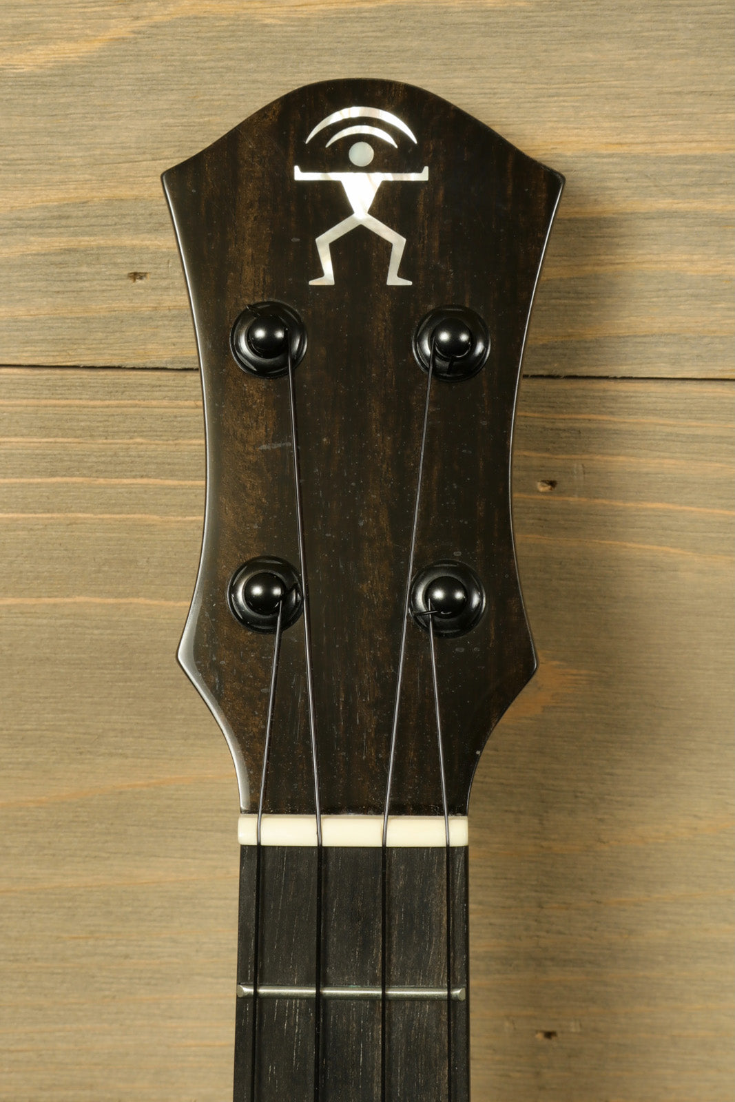 ANueNue UT200 ukulele, dark wood finish, close-up of the headstock with logo