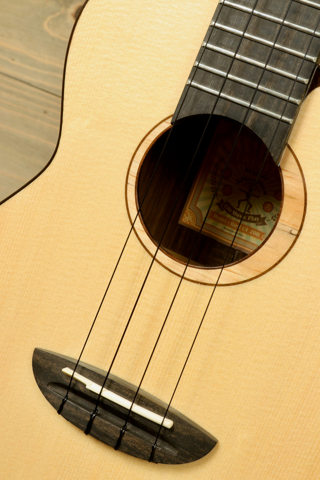 ANueNue UT200 ukulele in natural finish, close-up view of the body and strings