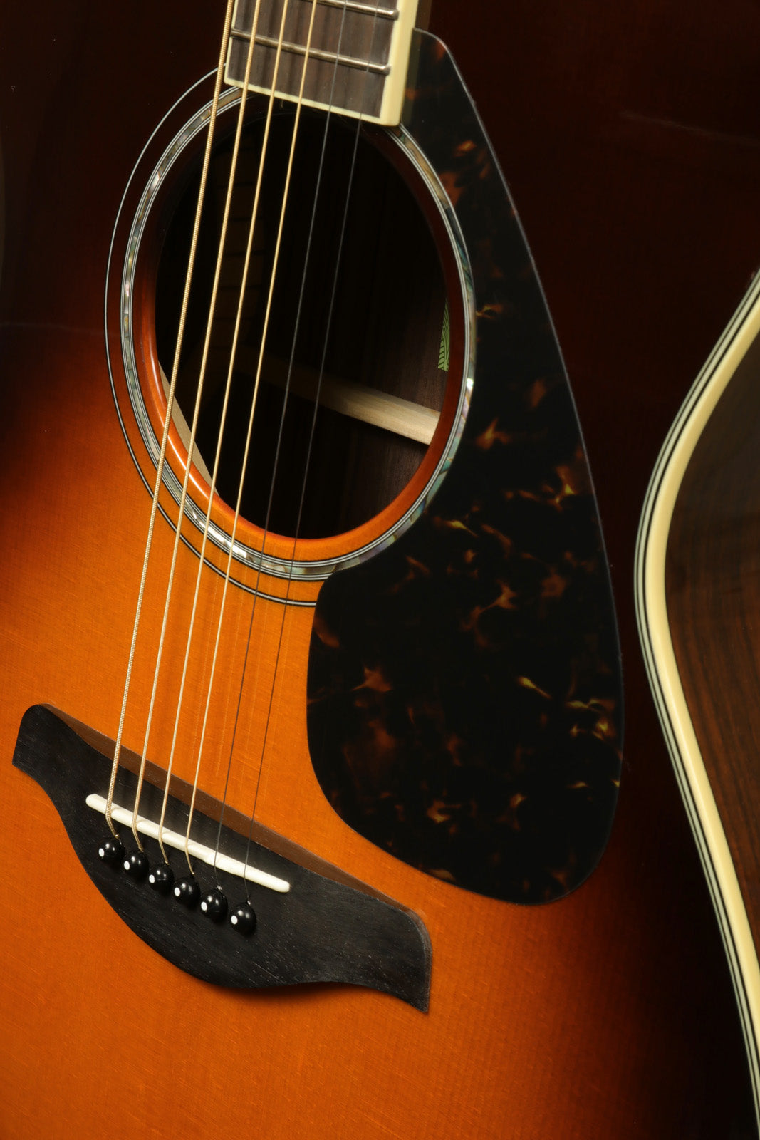 Yamaha acoustic electric guitar with sunburst finish and tortoiseshell pickguard, close-up view