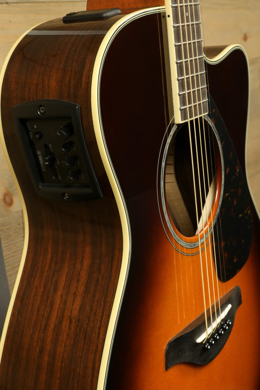 Yamaha acoustic electric guitar in sunburst finish, side view showcasing control panel and detailed wood grain