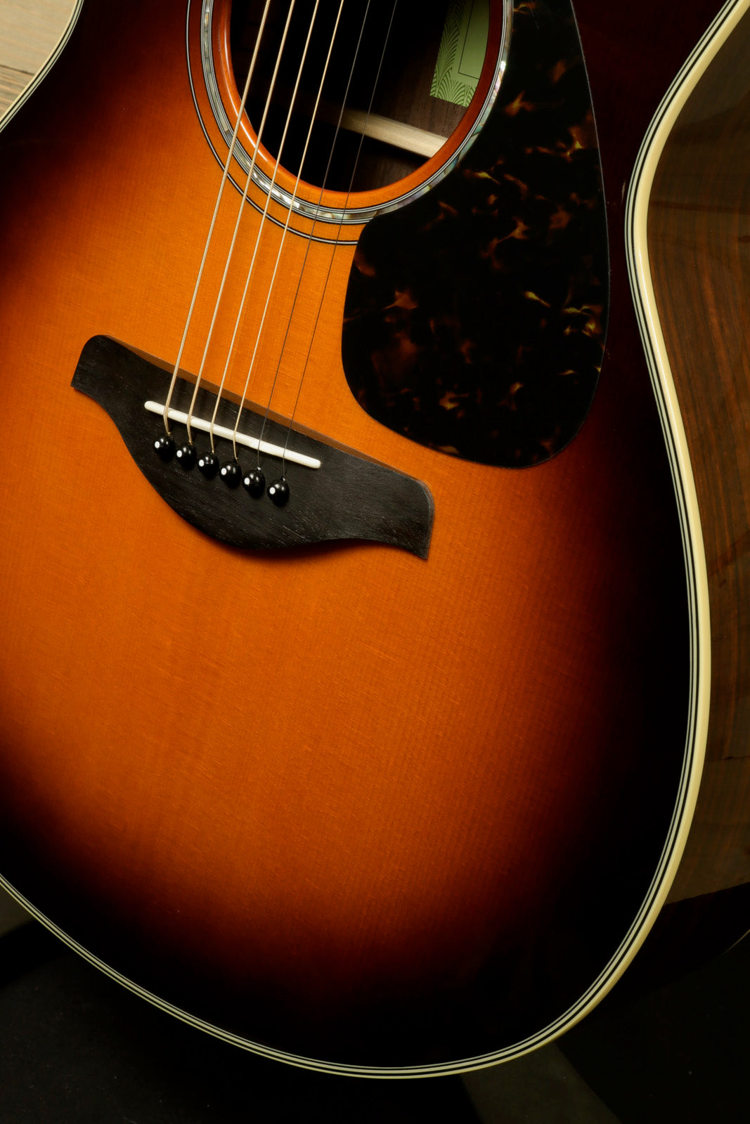 Yamaha acoustic electric guitar in sunburst finish, showcasing the body and tortoiseshell pickguard