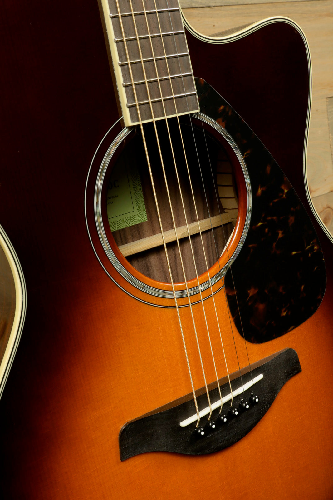 Yamaha acoustic electric guitar natural finish, close-up view of sound hole and strings
