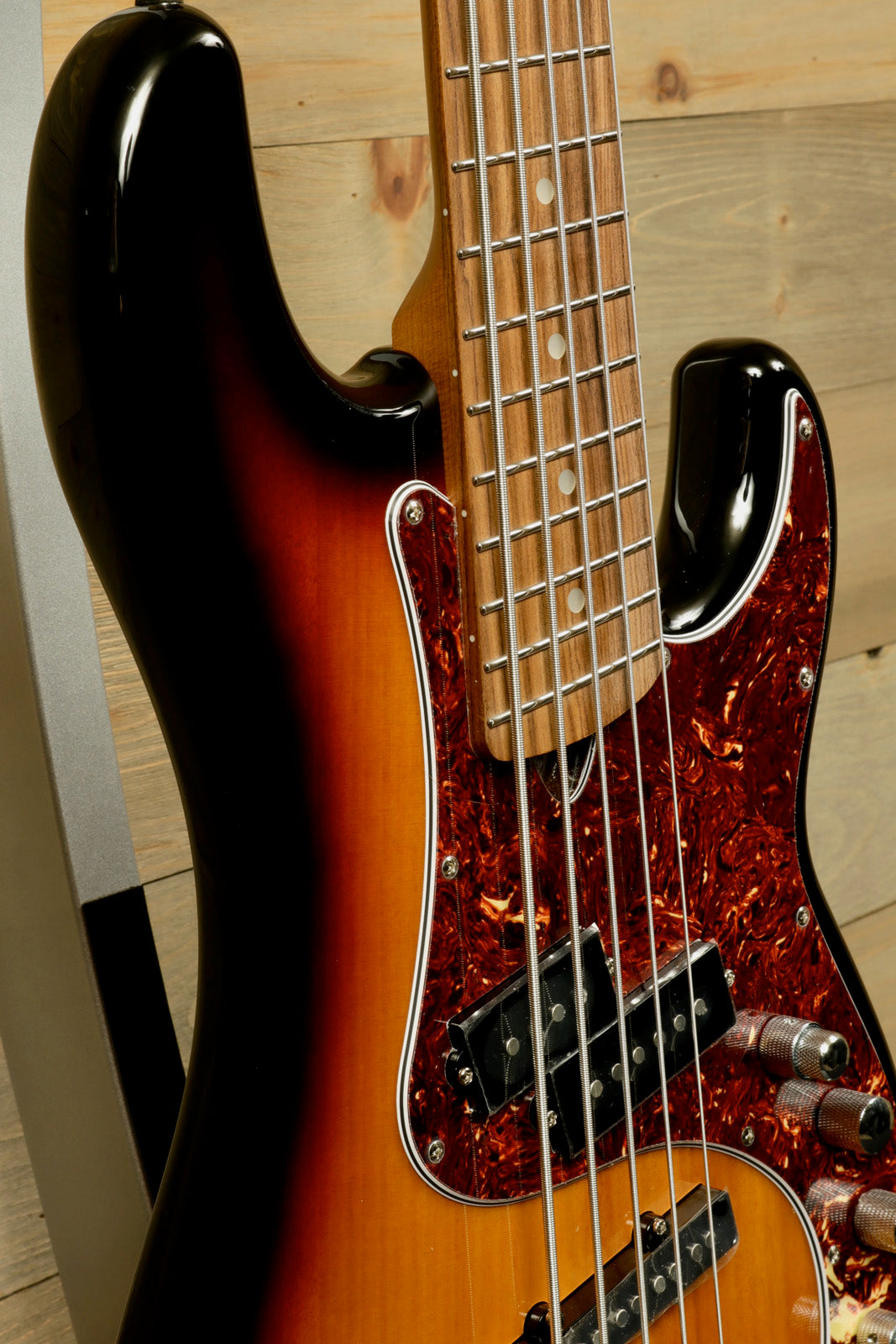 Tagima 5 string bass guitar with sunburst finish and tortoiseshell pickguard, close-up view