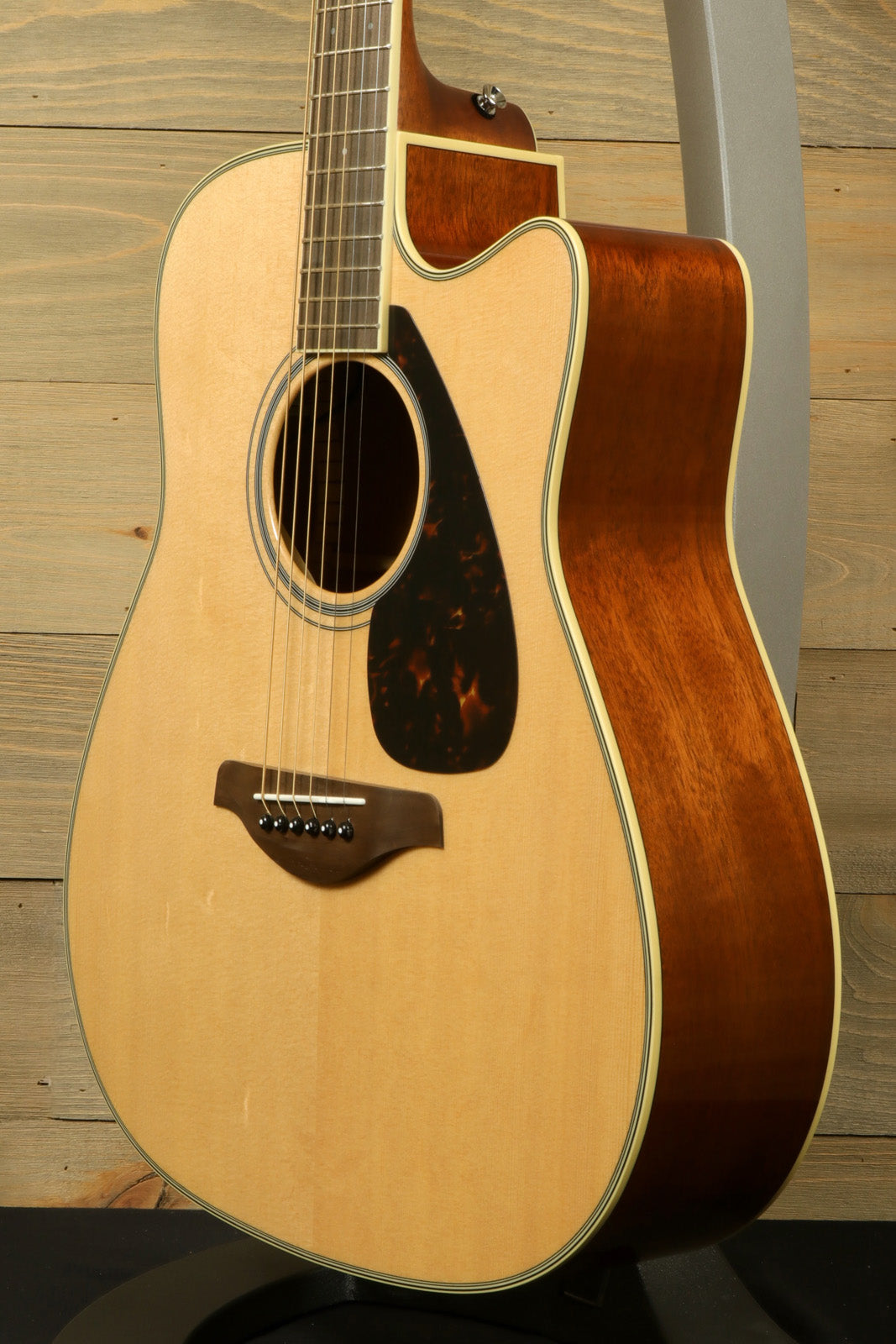 Yamaha acoustic electric guitar with natural finish, side view displaying craftsmanship and design.