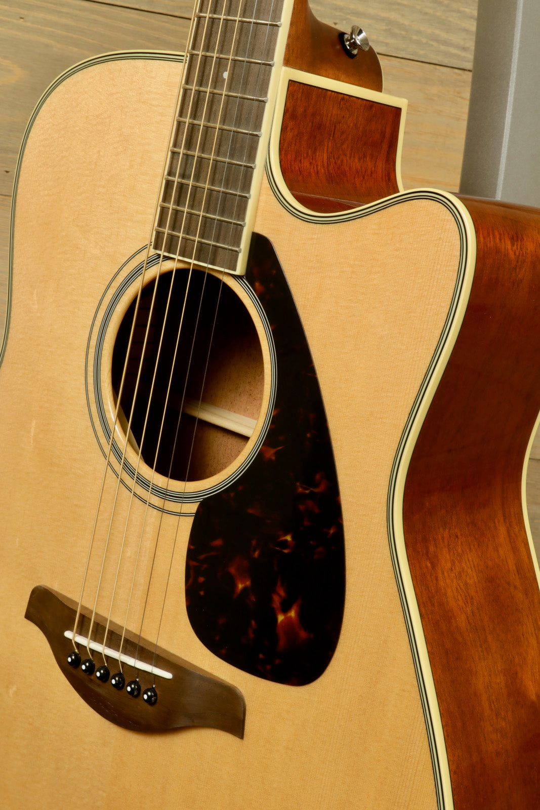 Yamaha acoustic electric guitar, natural finish, front view showcasing the soundhole and pickguard