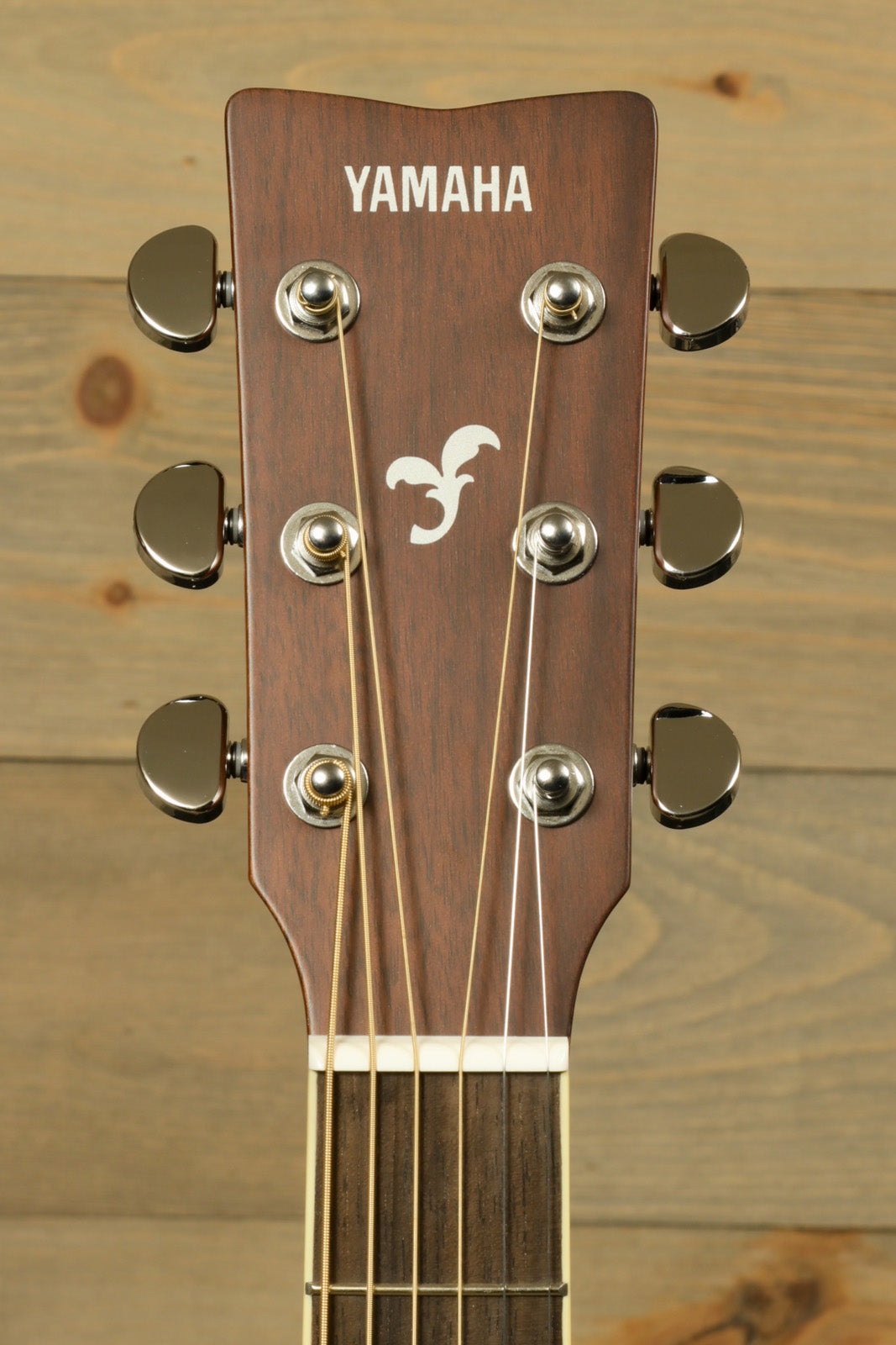 Yamaha acoustic electric guitar headstock with six tuning pegs and logo, top view