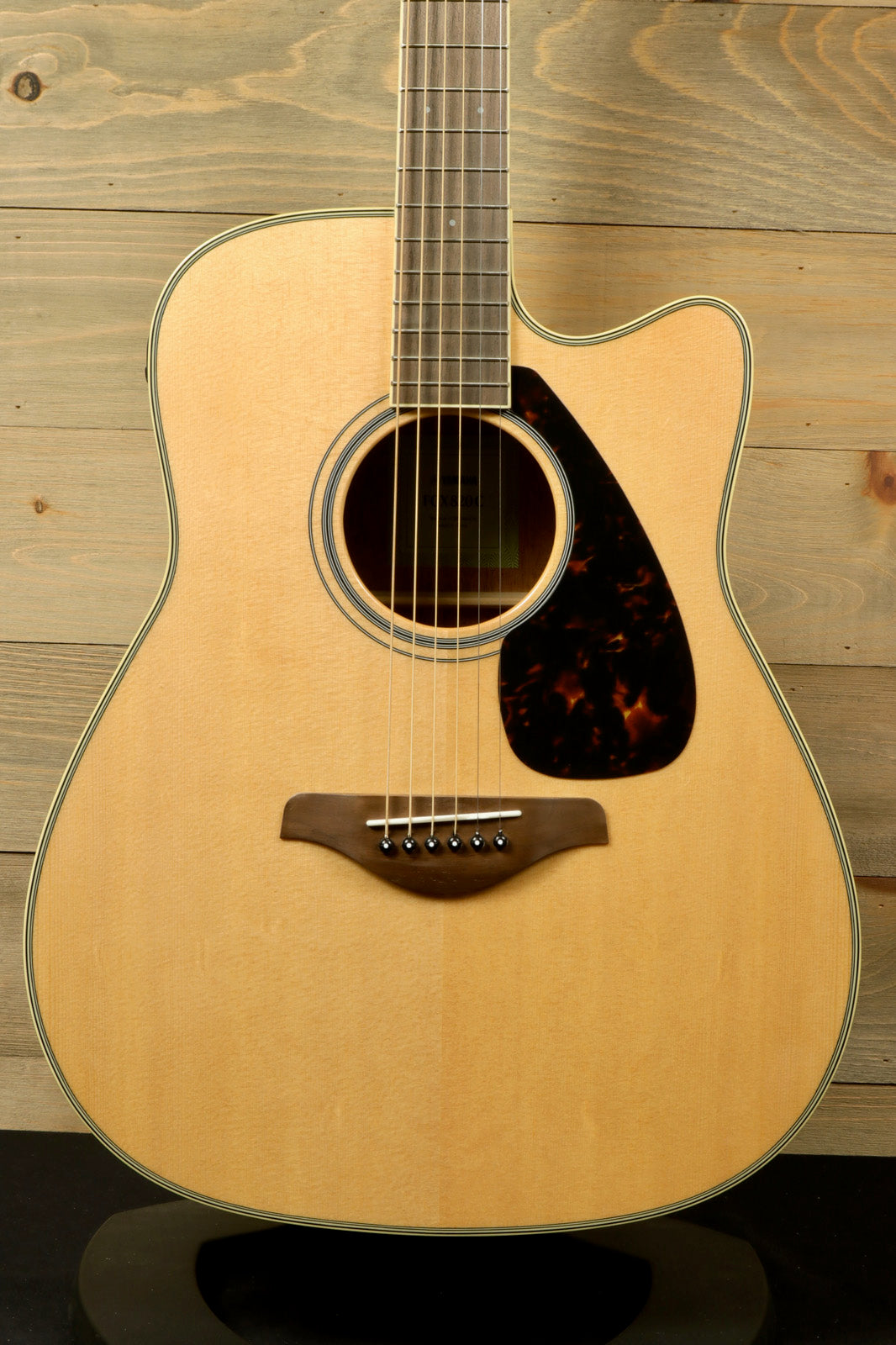 Yamaha acoustic electric guitar, natural finish, front view showcasing the body and pickguard details