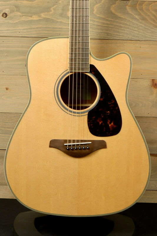 Yamaha acoustic electric guitar, natural finish, front view showcasing the body and pickguard details