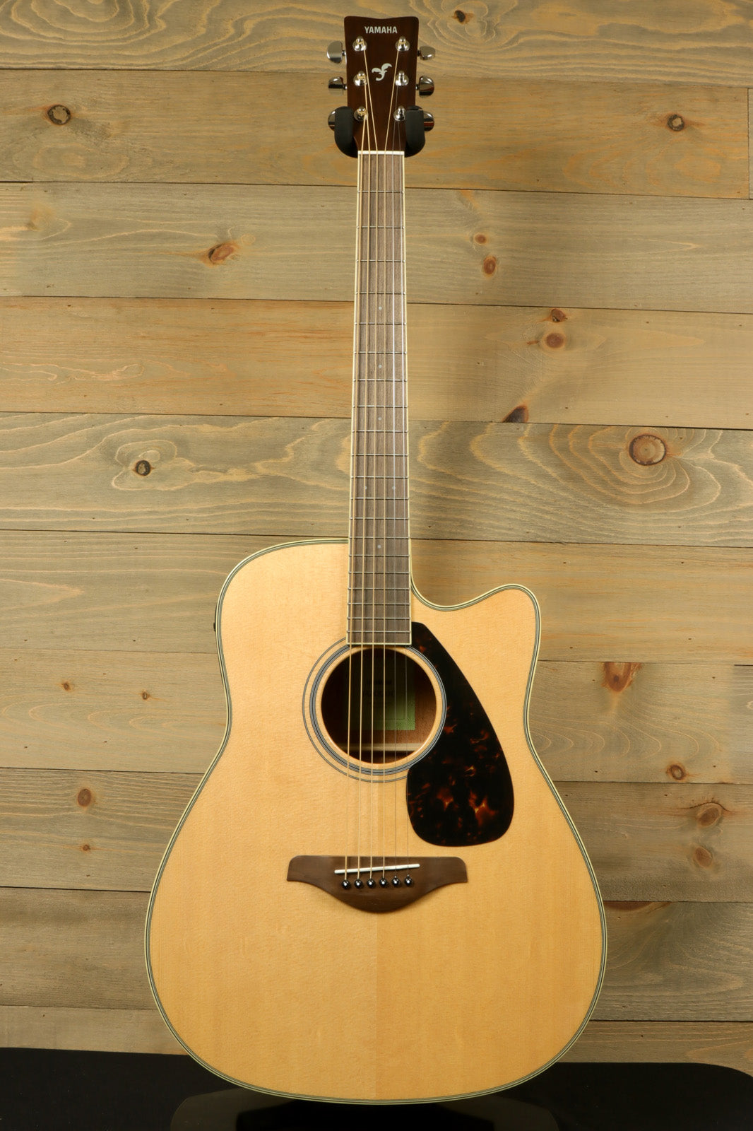 Yamaha acoustic electric guitar, natural finish, front view highlighting the body and neck