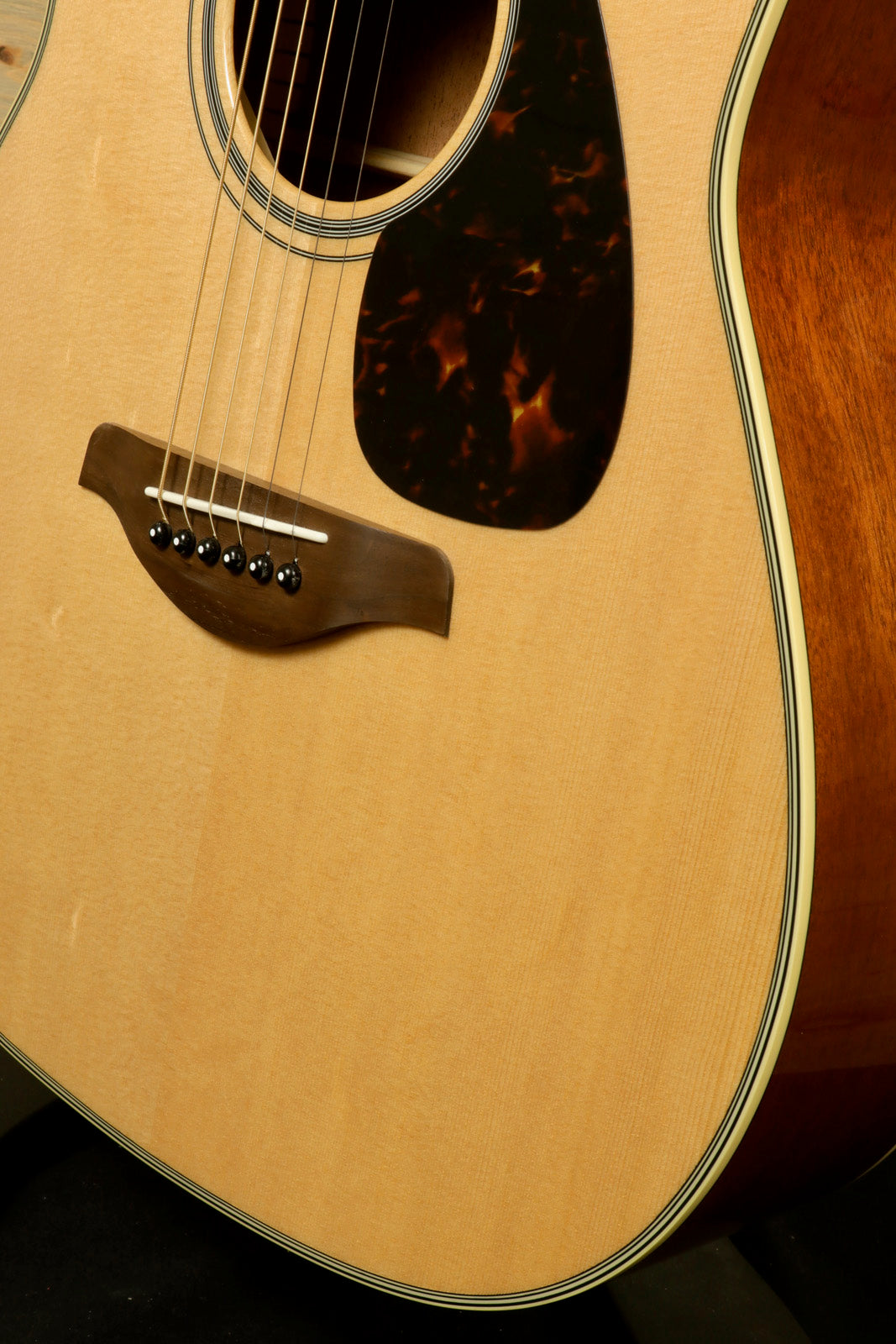 Yamaha electric and acoustic guitar, natural finish, close-up view of the body and soundhole