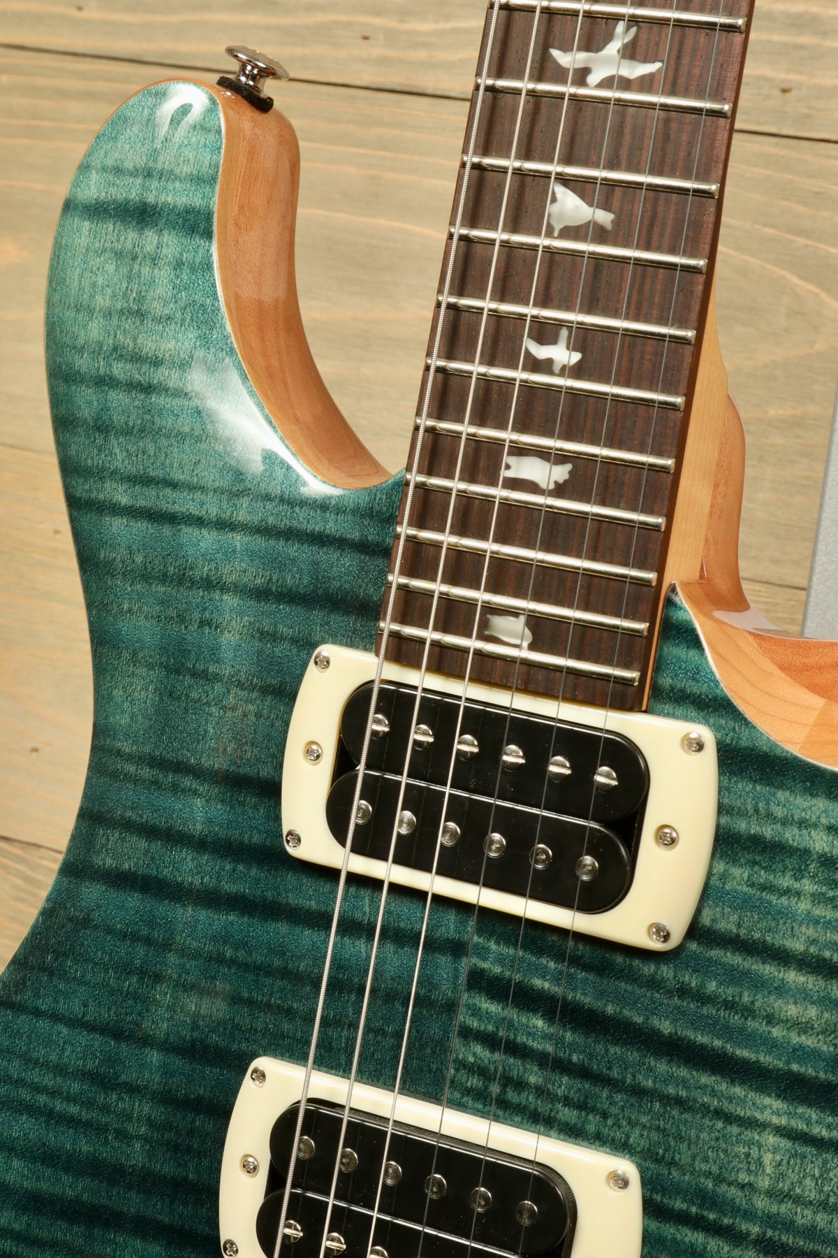 PRS electric guitar with blue-green finish and dual humbucker pickups, close-up view