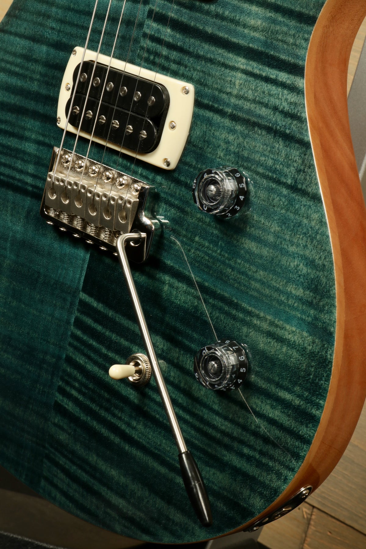 PRS electric guitar with a green finish, featuring a tremolo bridge and control knobs, side view