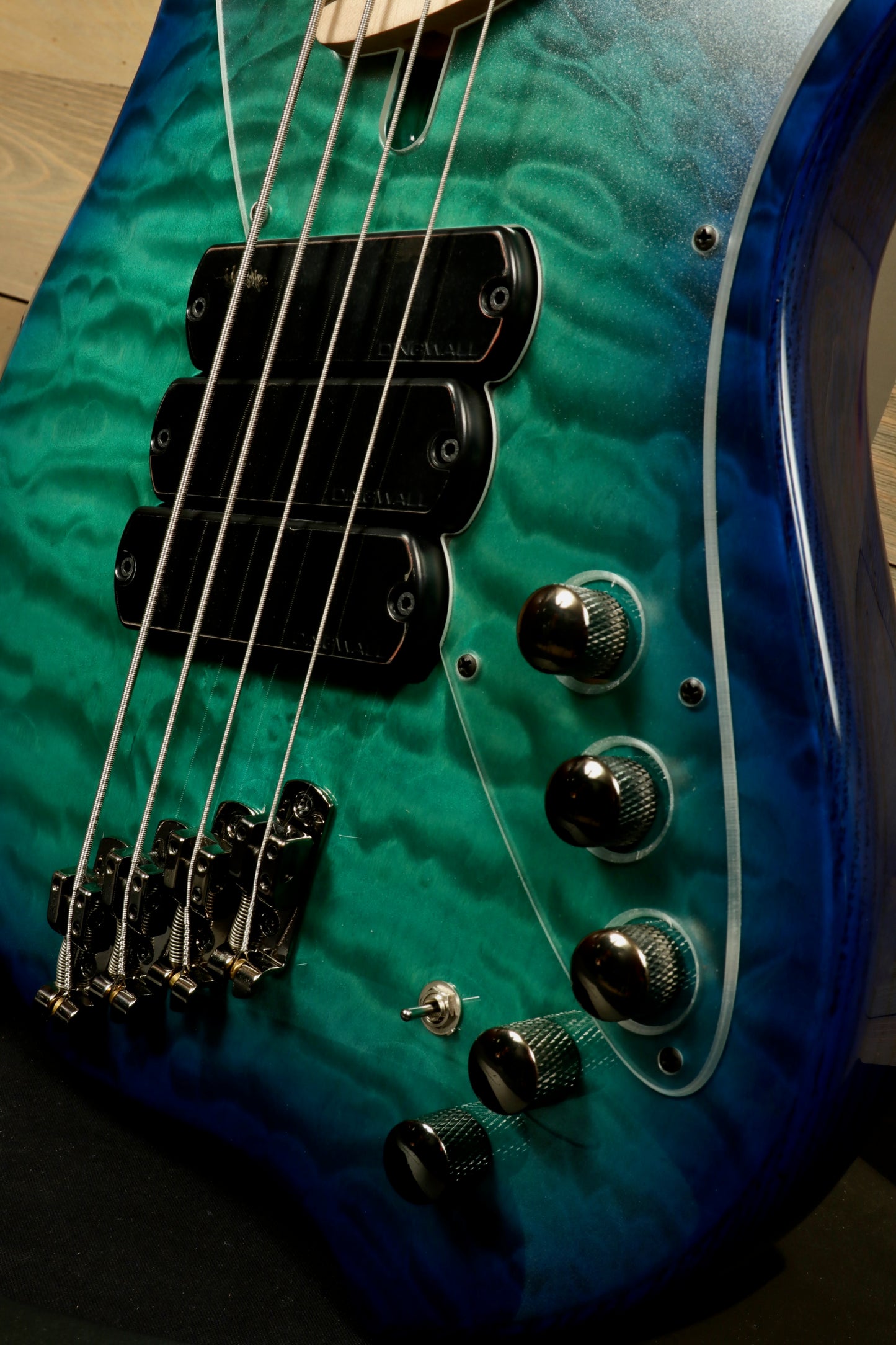 Dingwall Combustion Nashville bass guitar, blue-green quilted finish, close-up view of pickups and controls