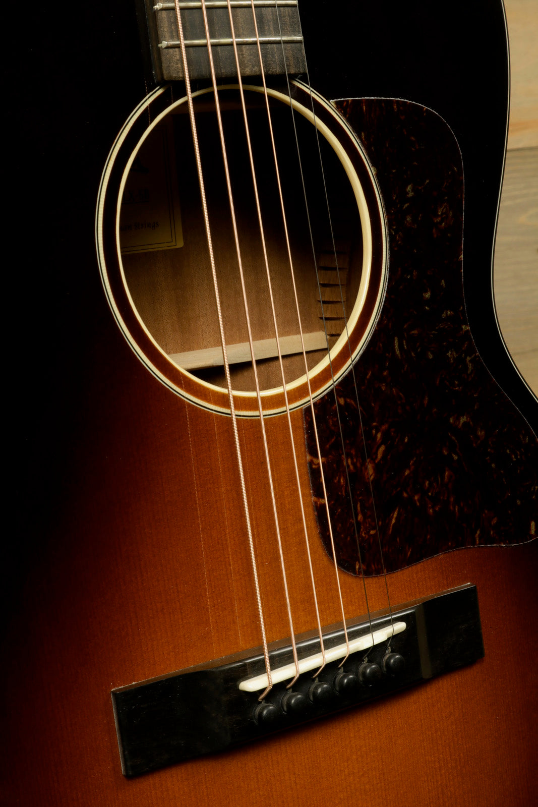 Eastman E1OOSS-DLX-SB acoustic guitar in sunburst finish, close-up view of the body and strings