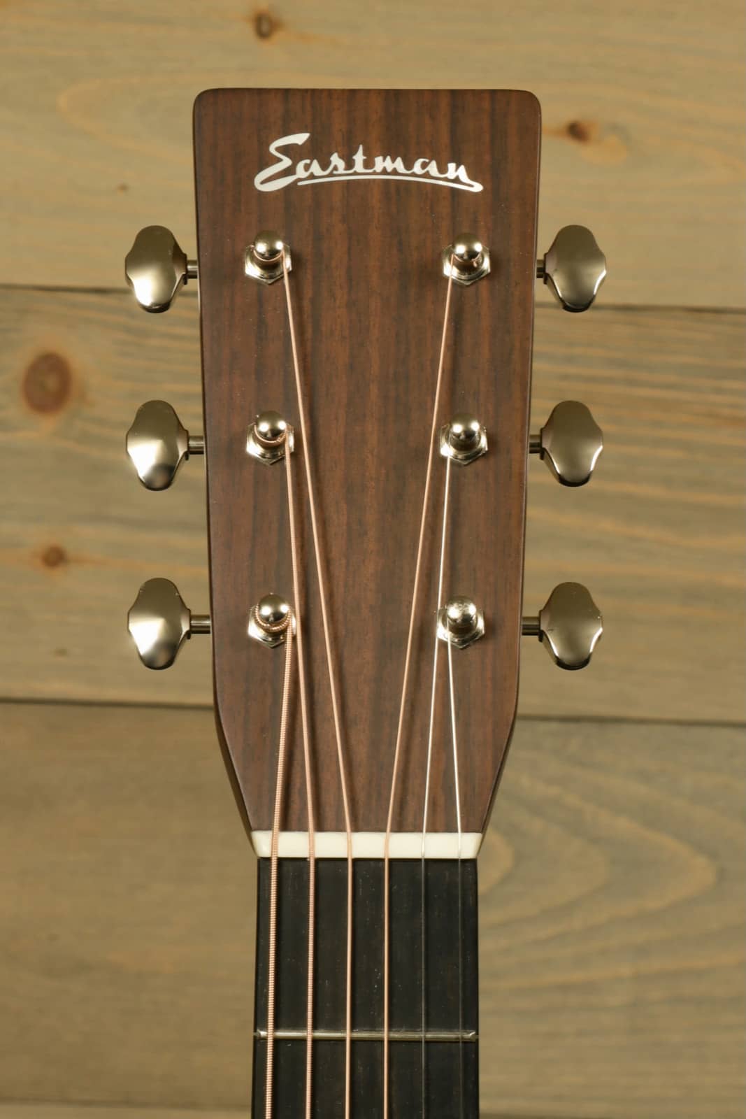 Close-up of Eastman E8OM-TC acoustic guitar headstock with tuning pegs and logo