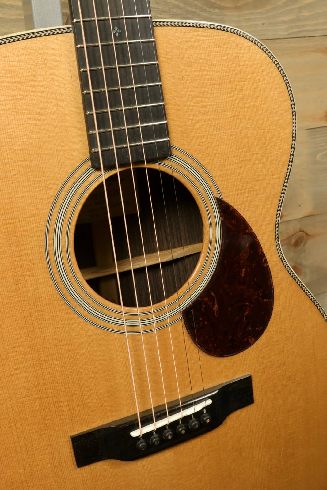 Close-up of Eastman E8OM-TC acoustic guitar with detailed wood grain and elegant soundhole design