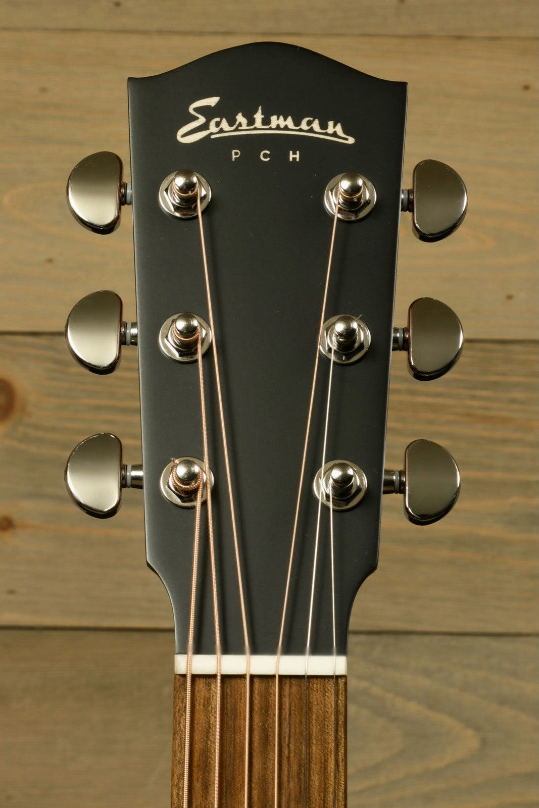 Eastman PCH1-OM acoustic guitar headstock in black finish, featuring elegant tuning pegs