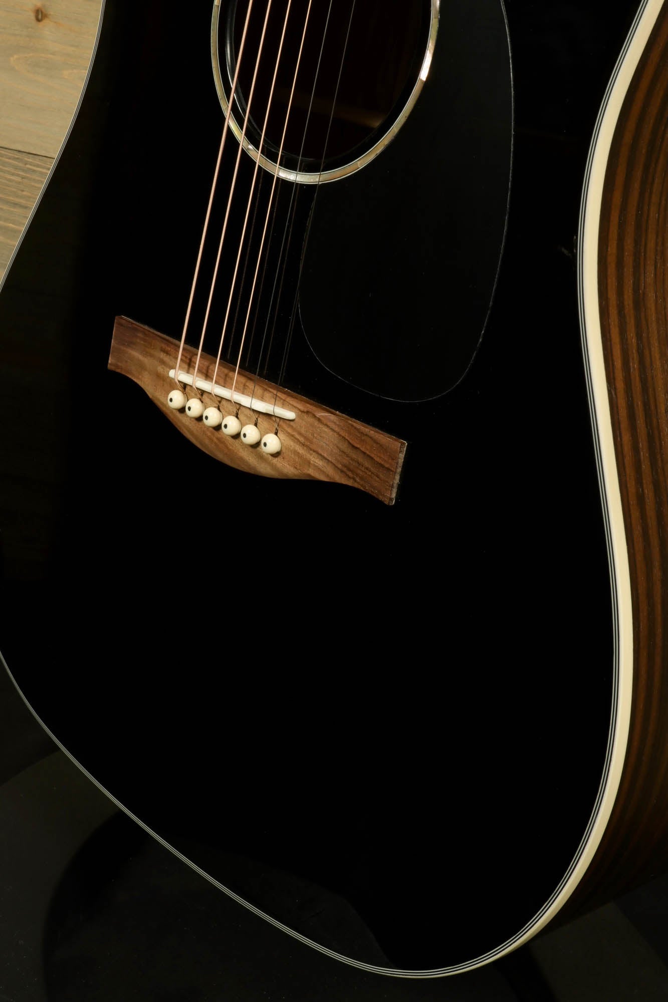 Close-up of Eastman PCH2-D-BK acoustic guitar with sleek black finish and walnut bridge