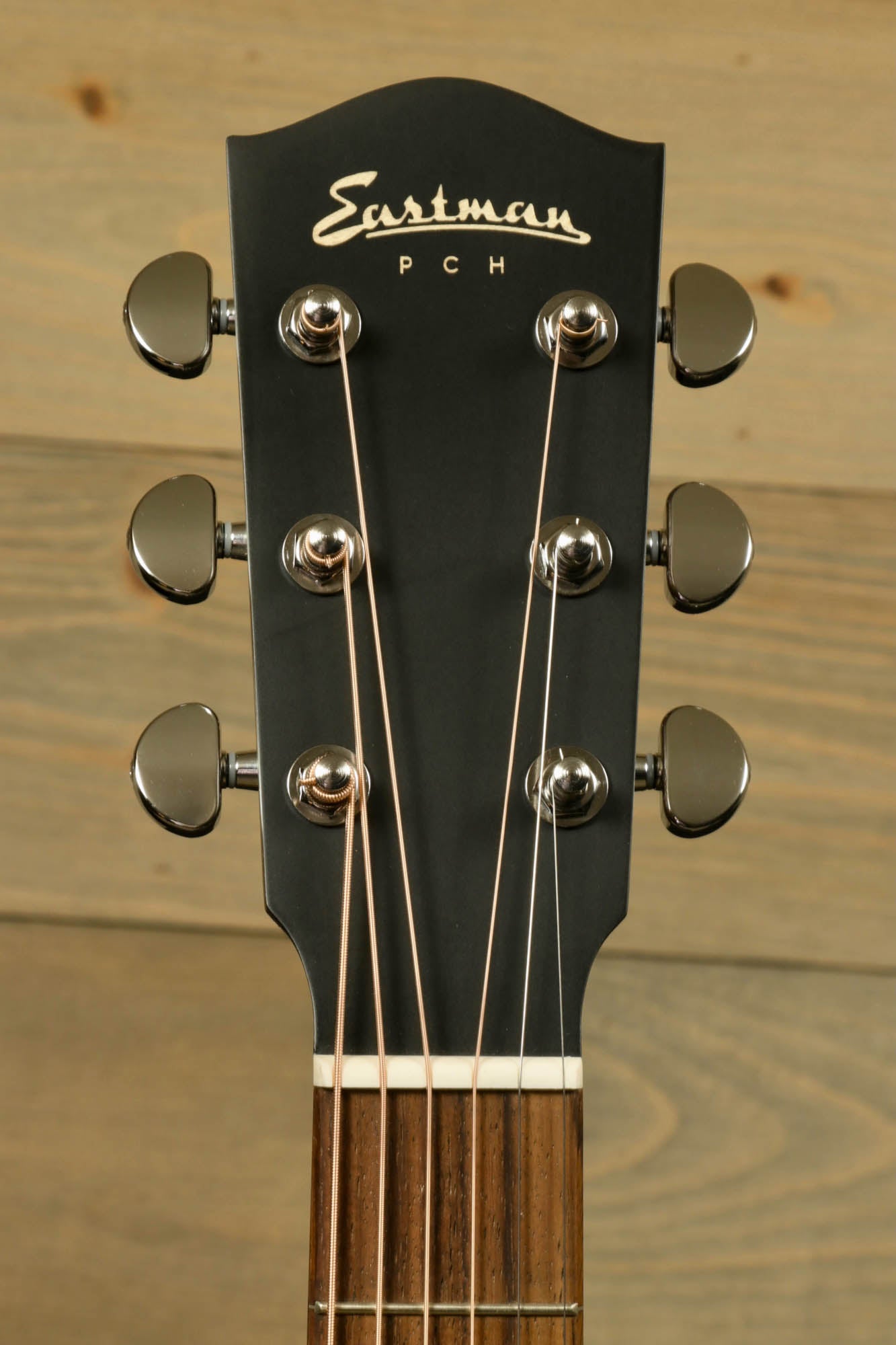 Close-up of Eastman PCH2-D-BK acoustic guitar headstock with tuning pegs and strings