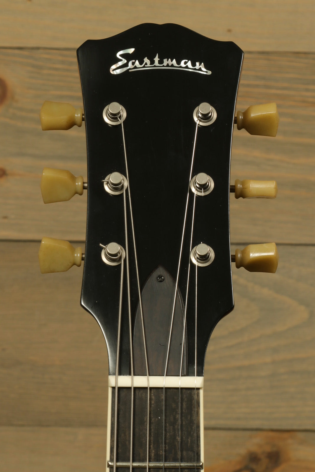 Eastman SB56/TV-AMB electric guitar headstock with golden tuning pegs, front view