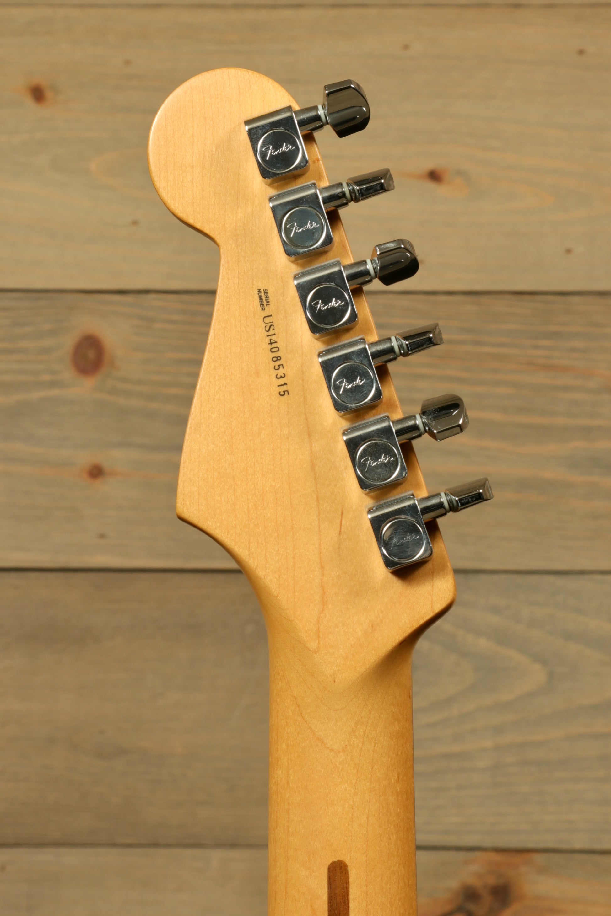 Close-up of headstock of used Fender American Standard Stratocaster HSS showing tuning pegs and wood finish