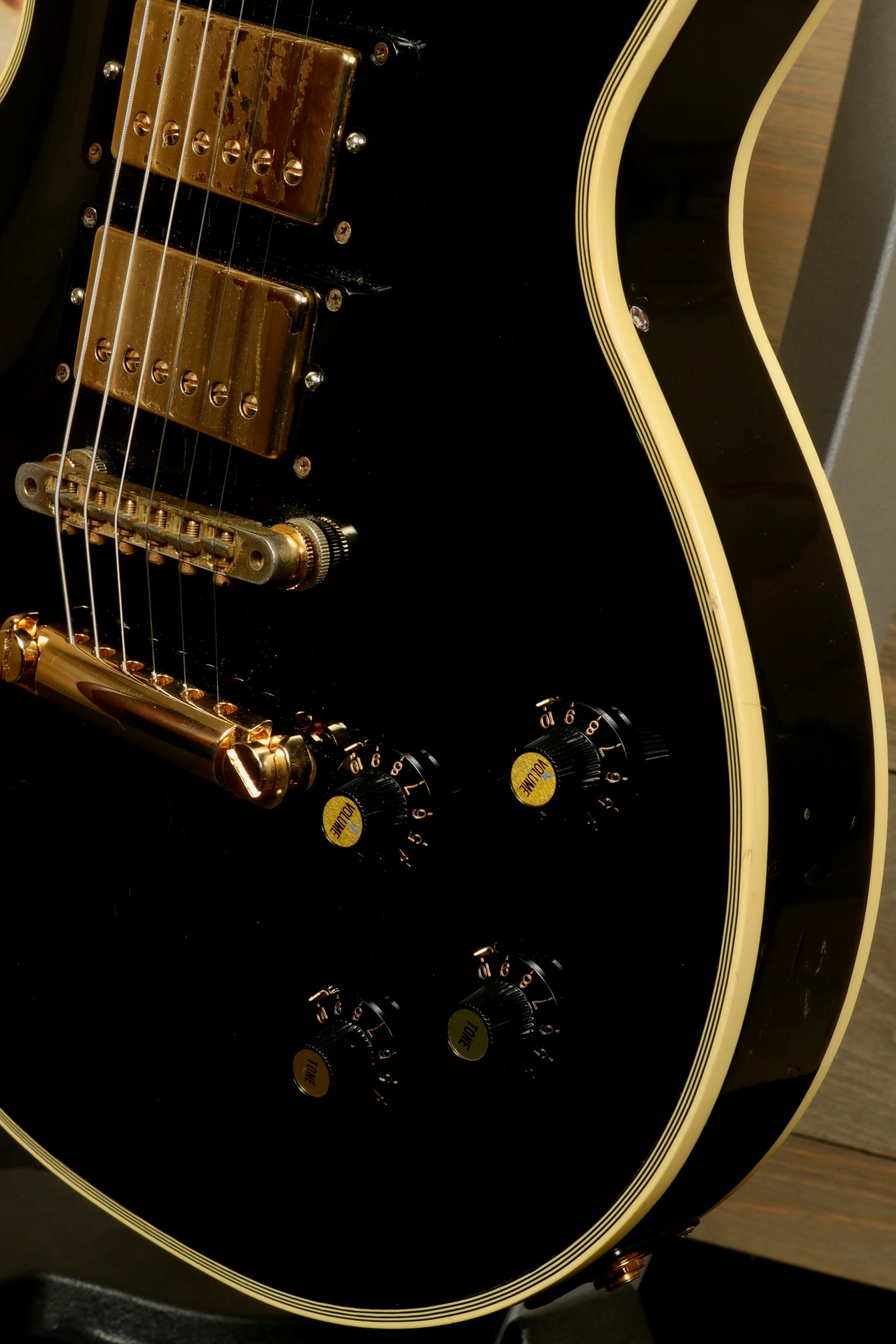Greco guitar, black electric guitar with gold hardware and control knobs, side view