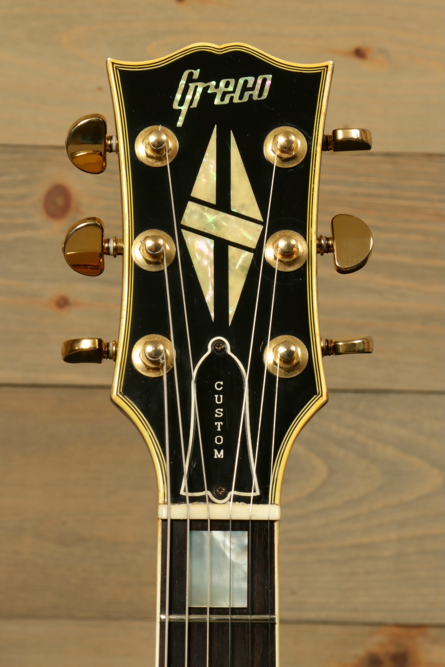 Greco electric guitar headstock with custom inlay and gold tuning pegs, front view