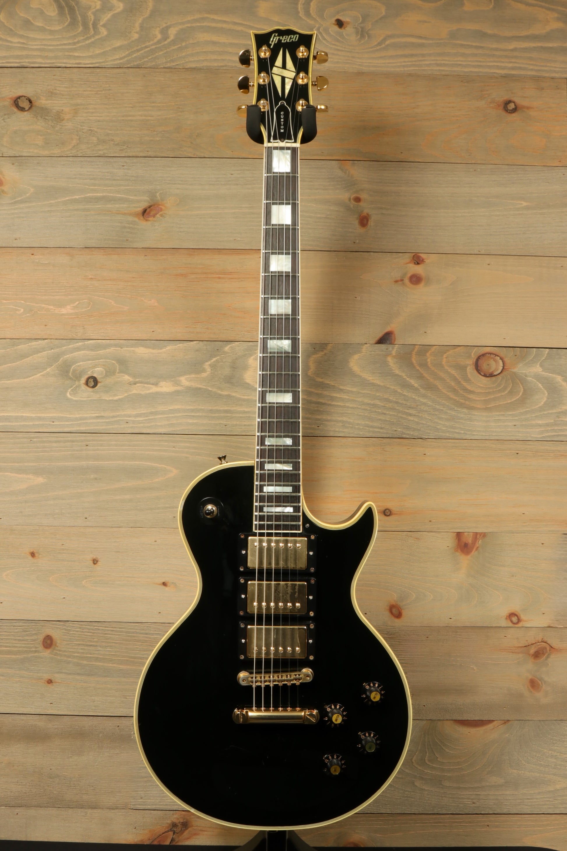 Greco electric guitar in black finish, front view with gold hardware and inlaid fretboard