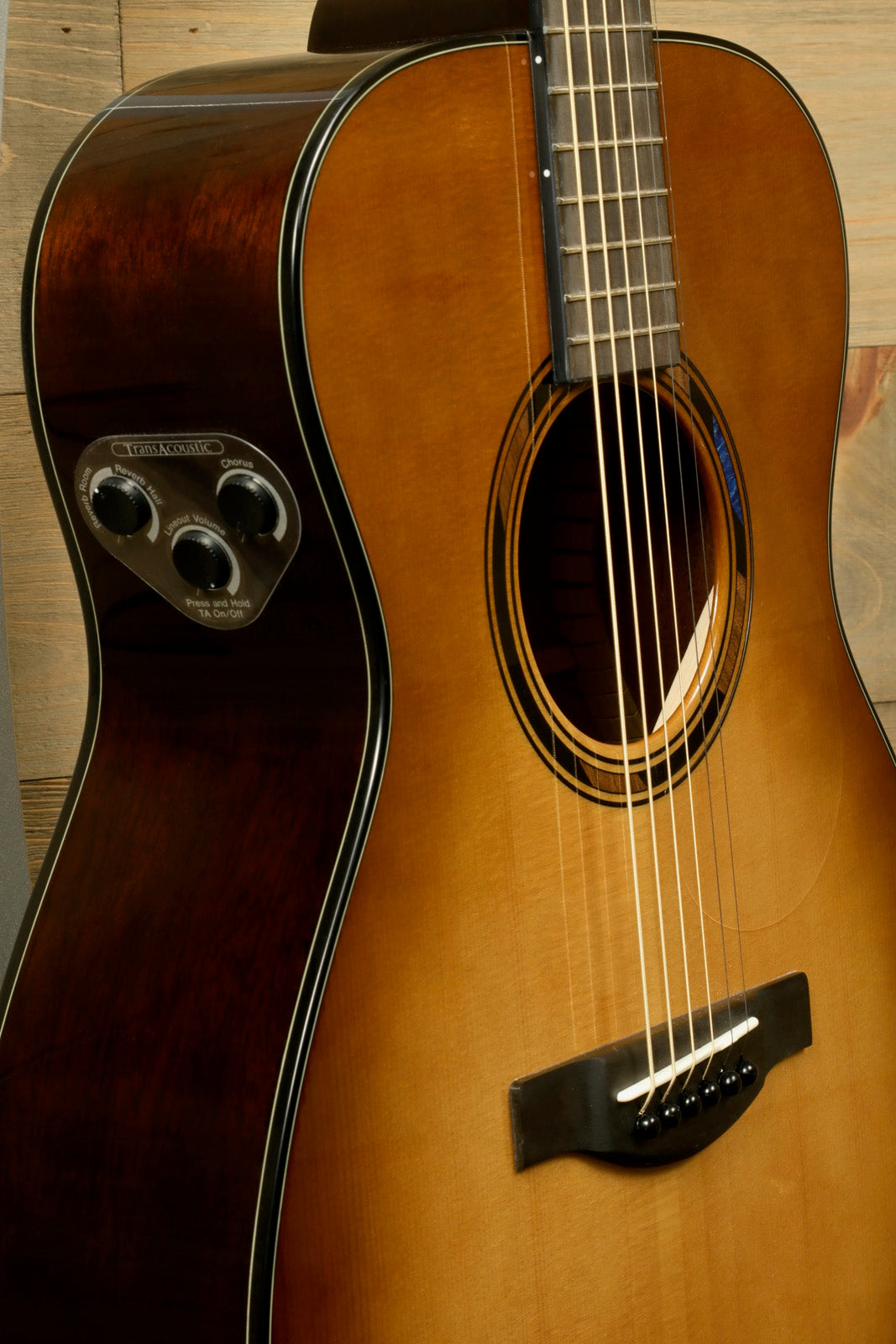 Yamaha acoustic electric guitar in natural finish, side view showing controls and strings