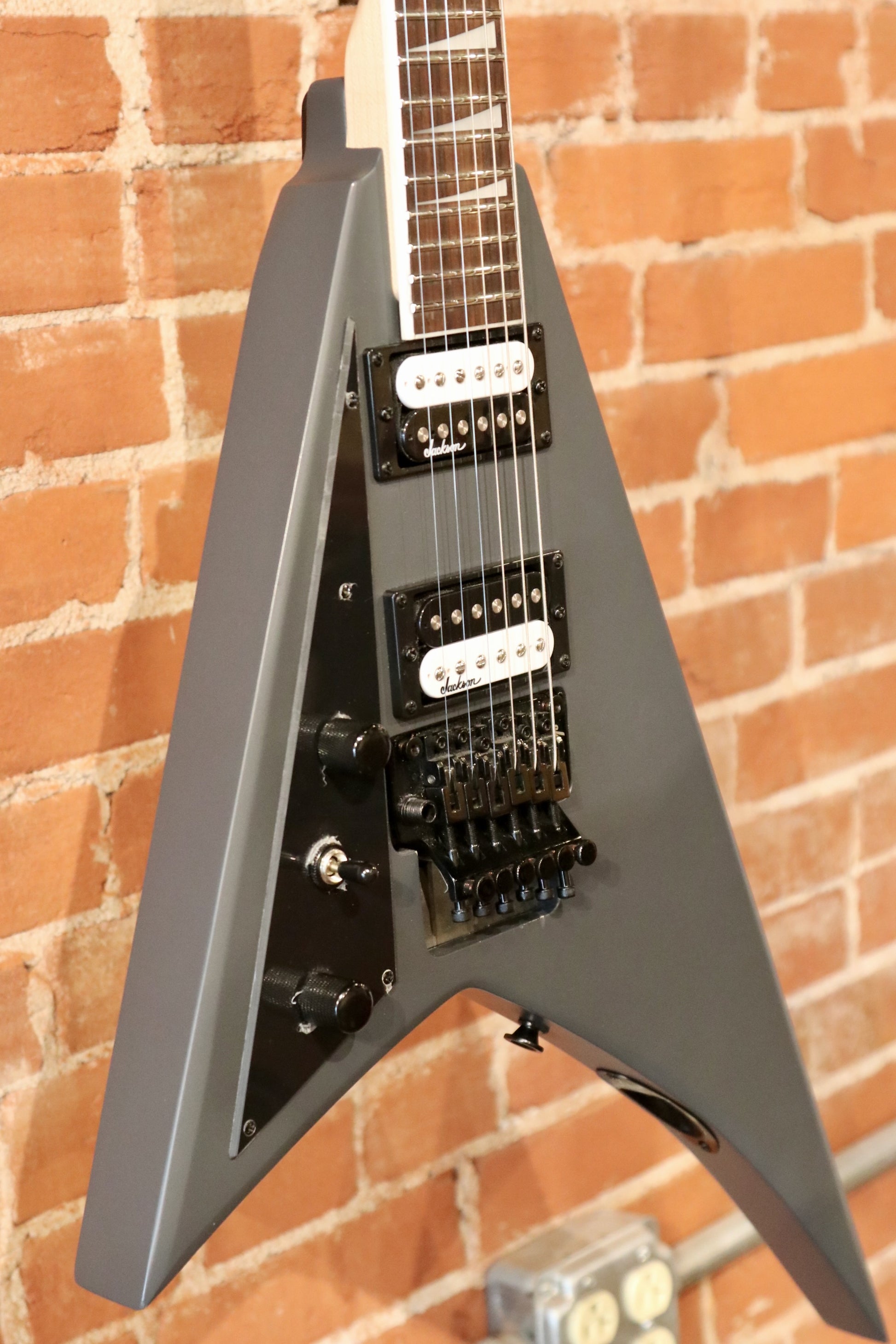 Jackson left handed guitar, gray finish, front view showcasing dual pickups and controls