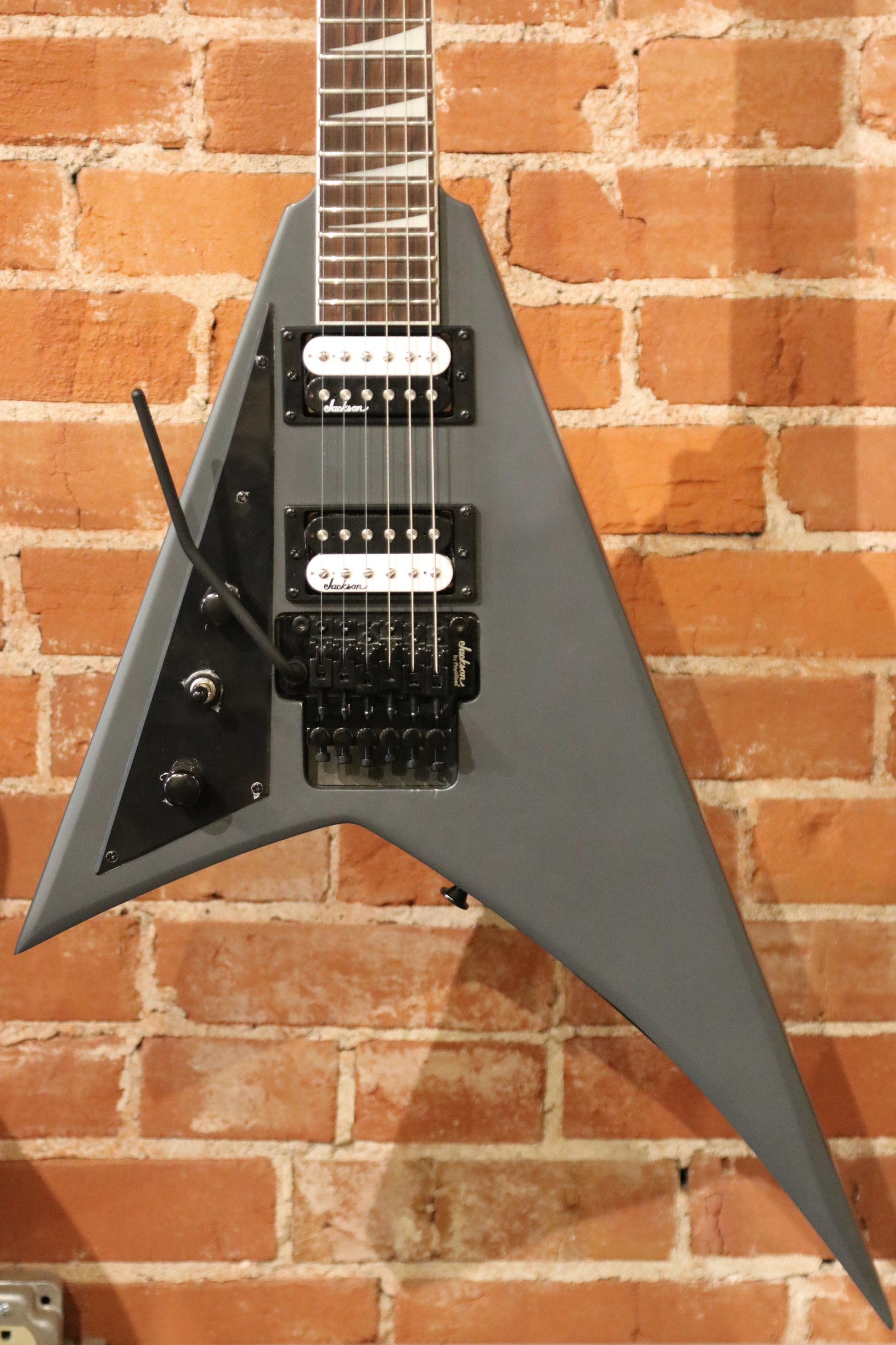 Jackson left handed guitar in gray, front view with double humbuckers and unique V shape
