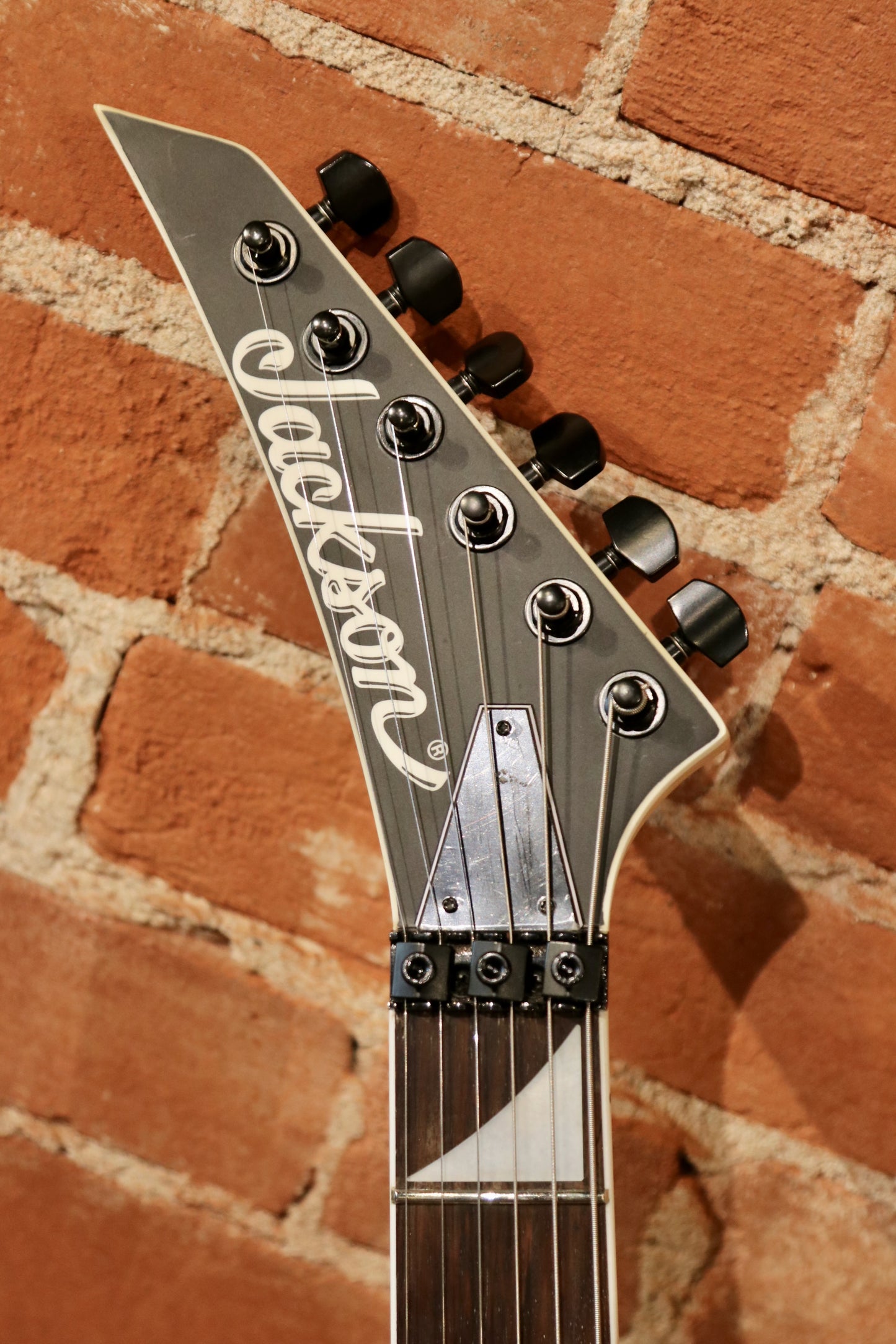 Jackson left handed guitar, black finish, close-up view of headstock and tuning pegs