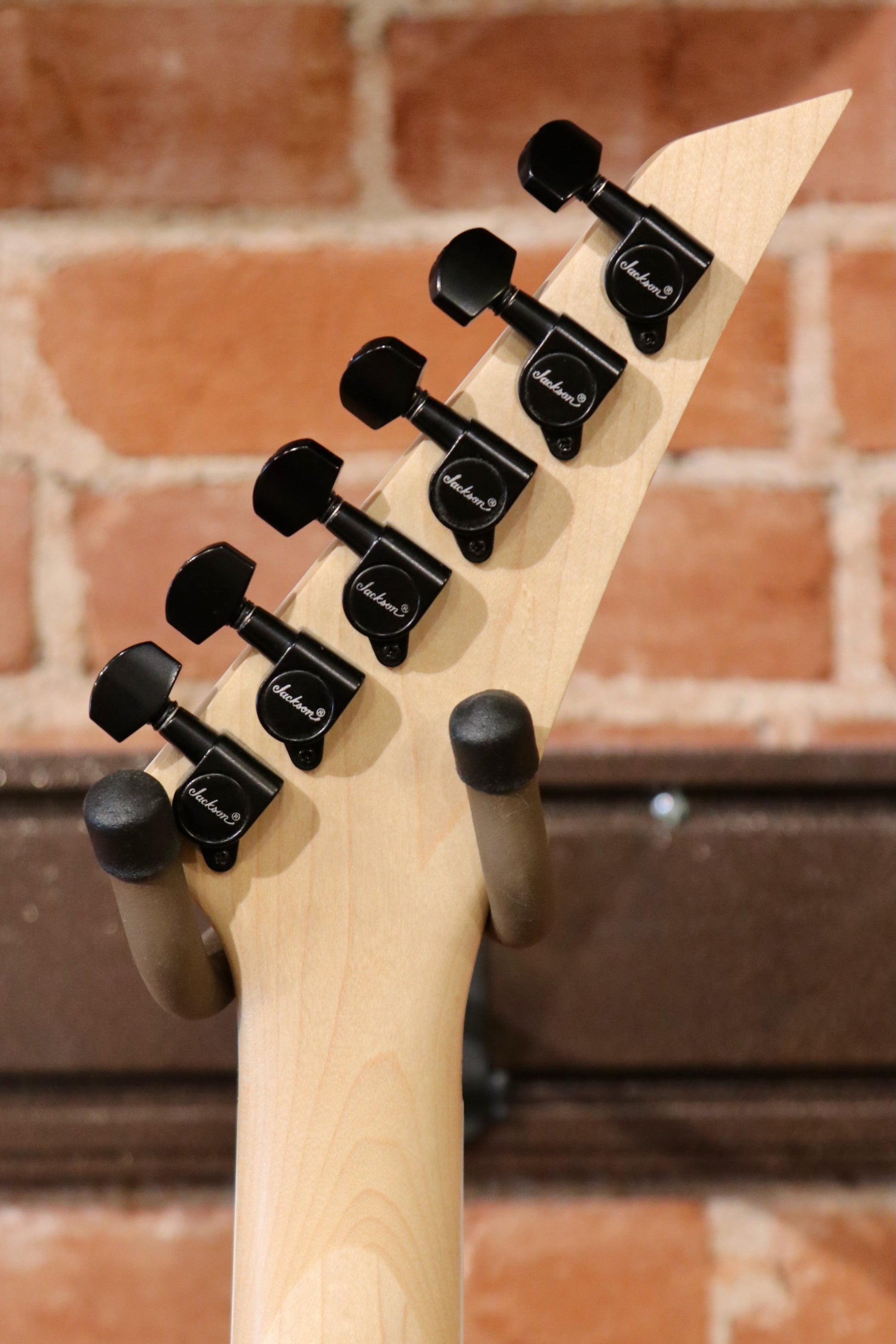 Jackson left handed guitar left handed, neck view with black tuning pegs on a natural wood finish
