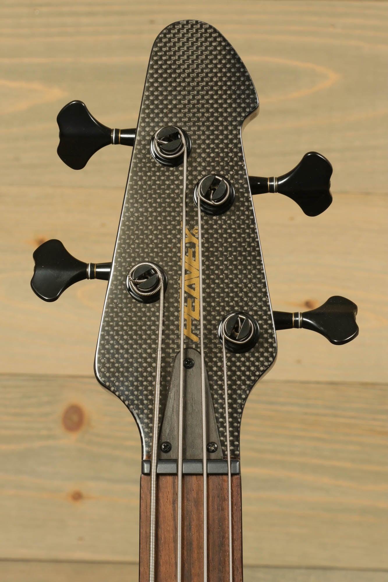 Close-up of the Peavey Cirrus 4 bass guitar headstock with tuning pegs and carbon fiber finish