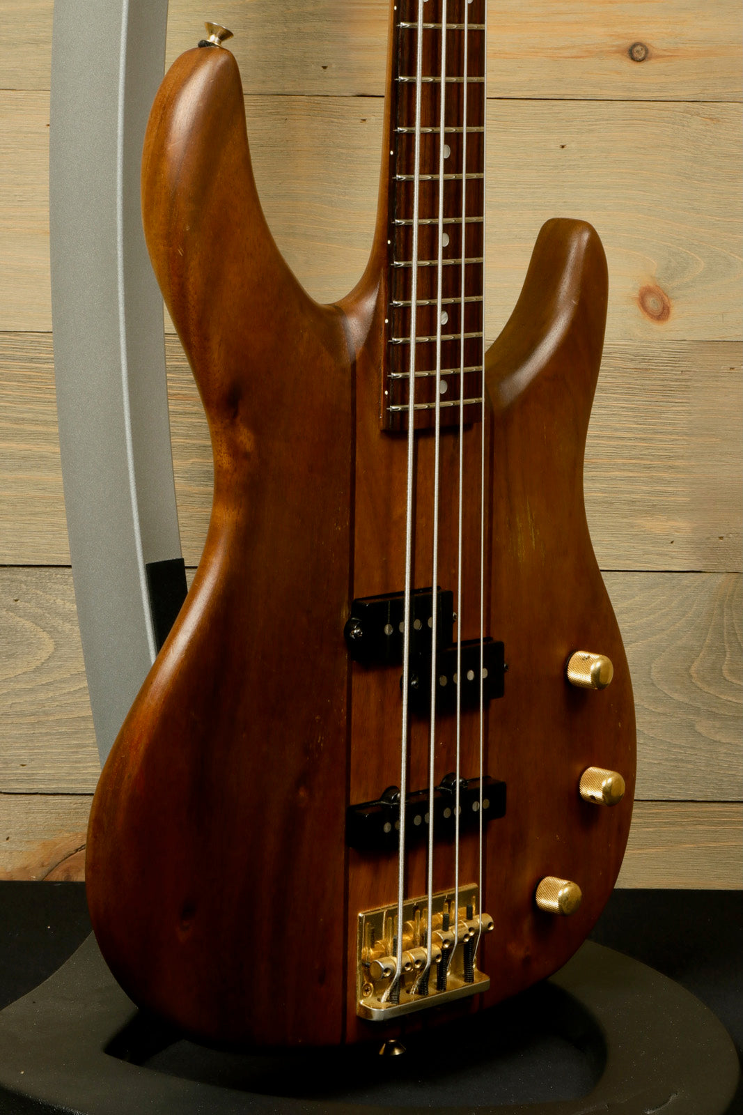 Peavey Vintage Peavey Unity Koa Bass guitar in natural wood finish, side view with controls