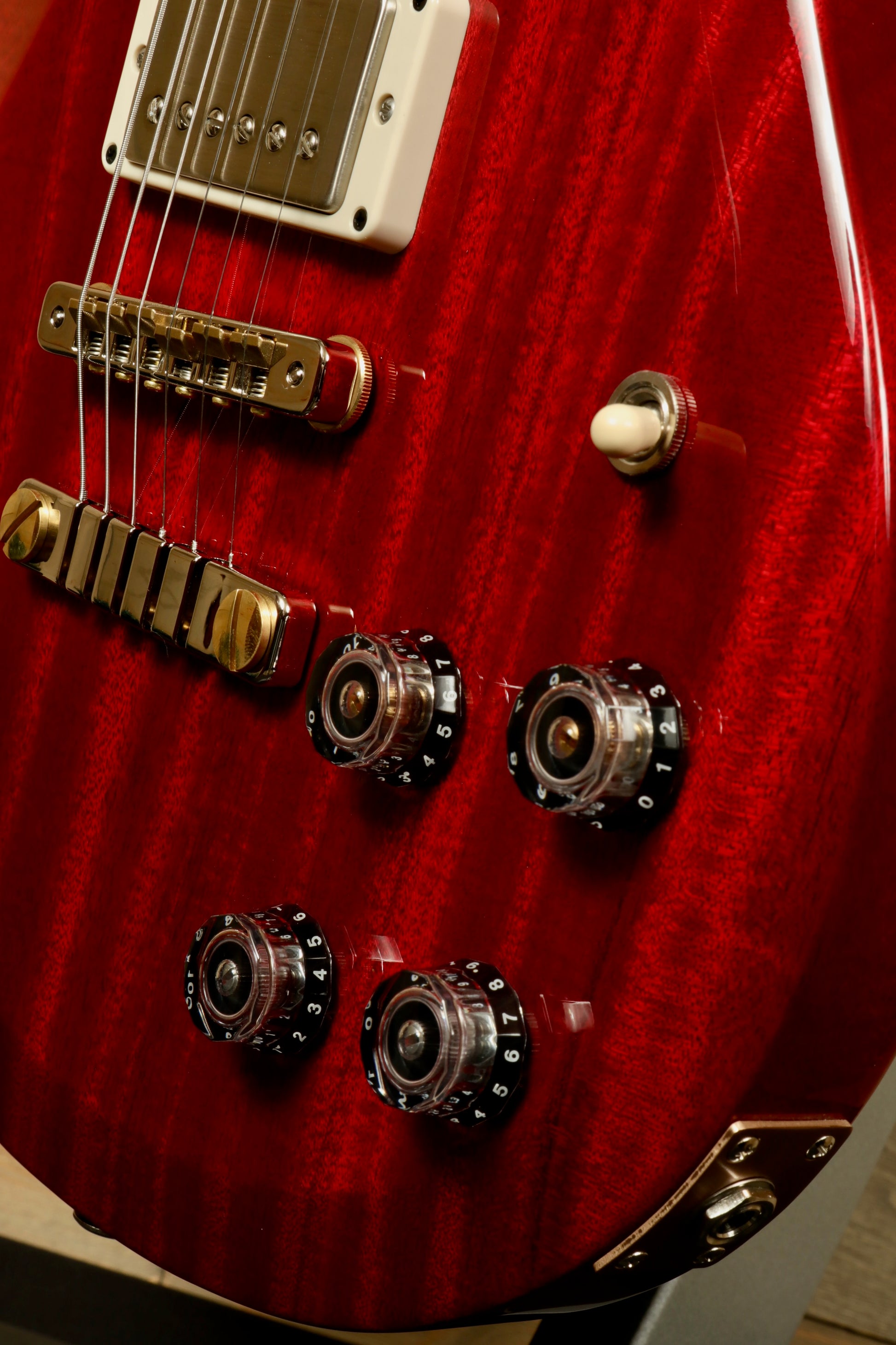 Close-up of PRS 594 McCarty electric guitar showcasing its rich red finish and control knobs
