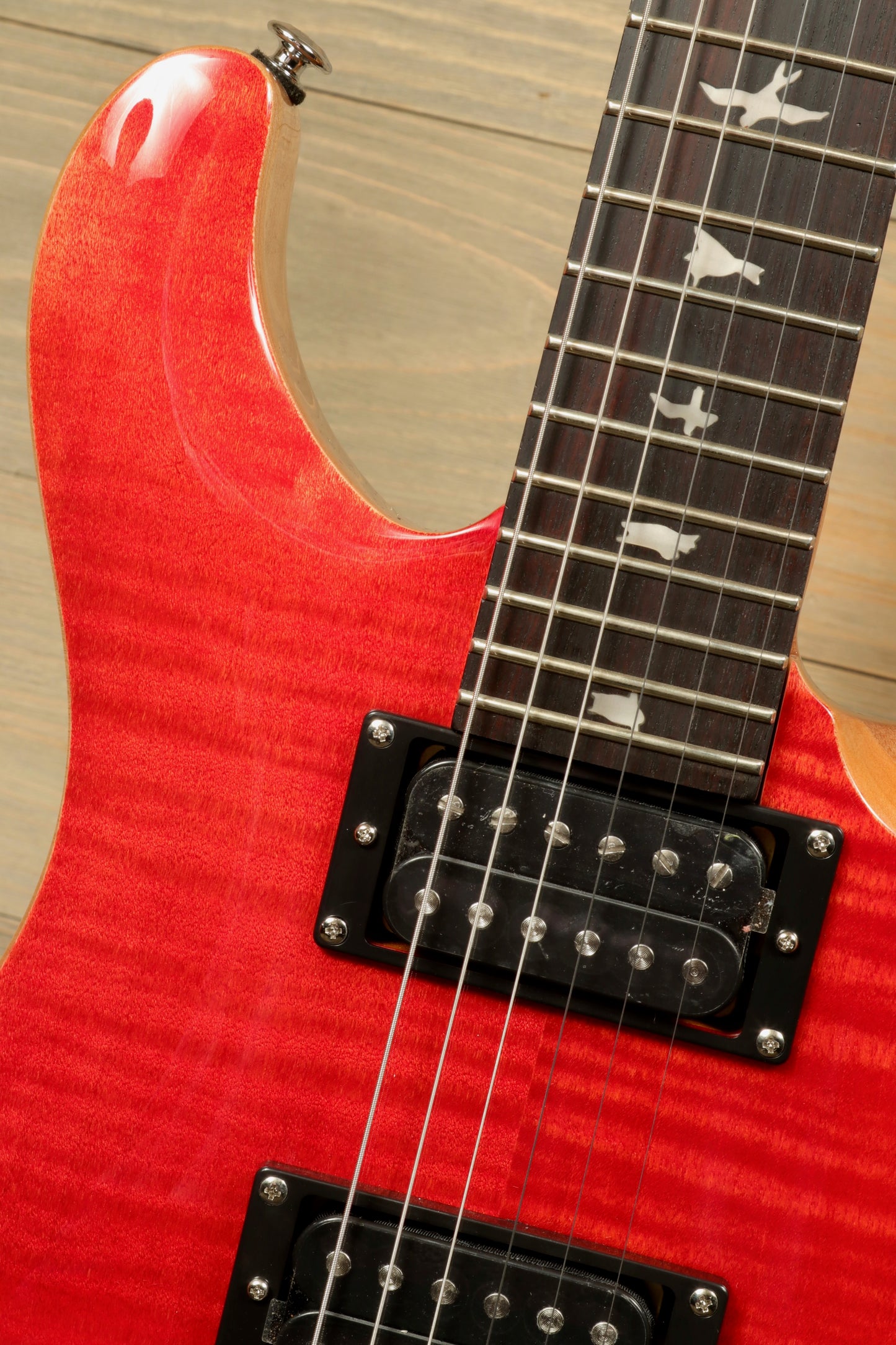 Close-up of PRS SE CE24 electric guitar showcasing the stunning red finish and detailed fretboard inlays