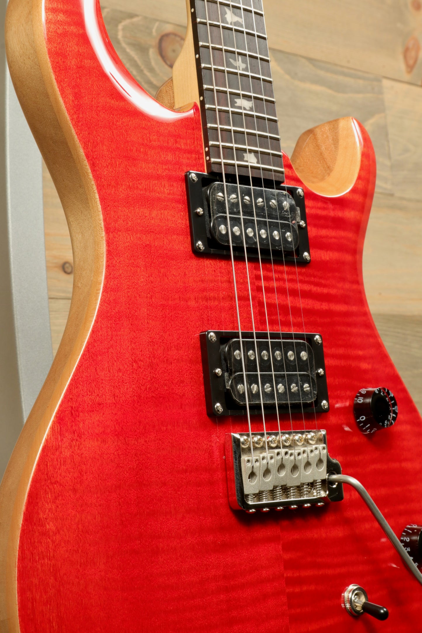Close-up of PRS SE CE24 electric guitar in vibrant red with humbucker pickups and control knobs